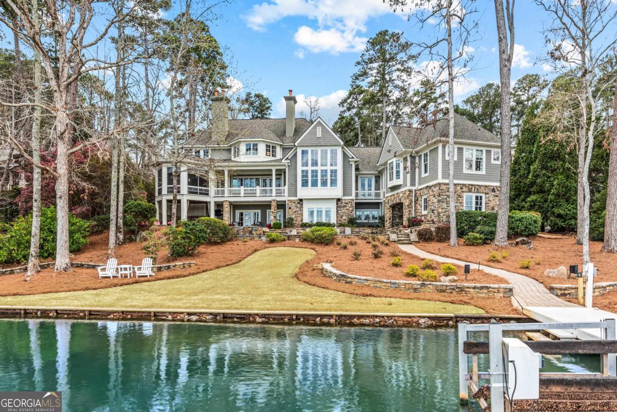 Step into this stunning lakefront home in Reynolds Lake Oconee, where expansive water views and luxury craftsmanship define the experience. The grand entry foyer, framed by double French doors, invites you to a breathtaking lake view, setting the tone for a home made for luxury lakeside living.  Designed by renowned architect Don Beck, this Jackson Ridge estate is one of the most desirable locations in Reynolds, celebrated for its expansive private waterfront lots, and breathtaking open-water views. The great room and dining area feature soaring vaulted ceilings, floor-to-ceiling windows, and a stacked stone fireplace as the centerpiece, creating a bright, welcoming space ideal for entertaining or unwinding with a view. At the heart of the home, the chef's kitchen boasts a large island, secondary bar seating, and premium appliances, designed for effortless entertaining and casual lakeside dining. The kitchen is adjacent to a balcony and spacious screened porch with grill overlooking the pool and lake.  The primary suite, located on the main level, offers stunning lake views and exceptional comfort. It features his and her closets and a wet bar/coffee station that seamlessly leads into the office/study, providing both convenience and privacy. The newly remodeled spa-like bath includes a soaking tub, oversized shower, and modern finishes, offering a serene escape.  The terrace level is built for entertainment and relaxation, featuring a secondary living area, full wet bar, and walk-out access to the private pool and firepit. A versatile bunk room with a rubber floor easily converts into a home gym for fitness enthusiasts. Outdoors, multiple gathering spaces, including a covered patio, stone-detailed pool deck, and lakeside firepit, maximize the enjoyment of lakefront living.  Located in the heart of Reynolds Lake Oconee, this property is minutes by boat to The Ritz-Carlton, with easy access to the National Golf Course, fine dining, shopping, and world-class amenities. Additional potential awaits with the unfinished space above the garage, perfect for a guest suite or private office, seamlessly connected by the porte-cochere.  This is a rare opportunity to own a luxury lakefront home in one of Georgia's premier golf and lake communities. Membership is available.