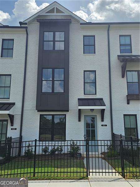 Enjoy living in this state of the art brand new just around 2000 sqft townhome (Glendale floorplan) built by Providence group which is located in Cumming's newest master-planned community, Sawnee Village. This smart home features 3 generous size bedrooms, 3.5 tiled bathrooms, lots of windows to allow for ample natural light, beautiful mountain view from the front of home, a fenced in private front yard, rear entry 2 car garage, level 2 car driveway, lots of windows to allow for ample natural light, a sunroom, beautiful mountain view from the front of home, a fenced in private front yard, 2 car garage, a level 2 car driveway, tall windows and doors, crown moldings throughout, nice light fixtures, EV charging available in the garage, a tankless water heater, climate controlled attic and a large deck perfect for entertainment. First floor features a nice size bedroom with French doors and a private full bathroom with a bath tub and shower combo, perfect for guests or a home office or an in-law suite. The main level features 9' ceilings, oversized dual-pane windows, and a sunlit open-concept layout. The kitchen features a 9' quartz island, white linen 42" soft-close cabinetry, Xenon under-cabinet lighting, and a 4x12 subway tile backsplash, ENERGY STAR Certified GE stainless steel appliances, including a side-in gas range, microwave, vent hood vented to exterior, dishwasher, and a refrigerator. The main level features 9' ceilings, oversized dual-pane windows, and an open-concept layout with lots of natural light. The kitchen boasts a 9' quartz island, white linen 42" soft-close cabinetry, Xenon under-cabinet lighting, and a 4x12 subway tile backsplash. Enjoy ENERGY STAR Certified GE stainless steel appliances, including a side-in gas range, microwave, vent hood vented to exterior, dishwasher, washer dryer and a refrigerator. The oversized private rear deck is equipped with GFCI outlets, perfect for grilling or lounging. The level also includes elegant 5" crown and base molding throughout. The top level features a spacious owner's suite featuring a walk-in closet, soaking bath tub, separate walk-in shower, and dual quartz vanity with linen cabinetry. The top level has a laundry room with a washer & dryer, linen closet and two spacious bedrooms including master and very nicely finished bathrooms. A secondary guest bedroom with its own private bath is located at the front of the home. Laundry is conveniently positioned just outside the owner's suite. Additional smart features include a Nest Video Doorbell, Nest Hub 7" Display, and WiFi Mesh Point. Sawnee Village offers exceptional access to GA-400, top Forsyth County schools, and future on-site retail/dining. The neighborhood also features a lot of guests parking spots and is located mins from to GA-400, top Forsyth County schools, and future on-site retail/dining. This is the only new townhome community walkable to retail, dining, and entertainment and shopping coming soon to Market Square within the complex. Please go to Providence group builder website to see a video tour of this beautiful and decorated model to visualize the home in decorated state.