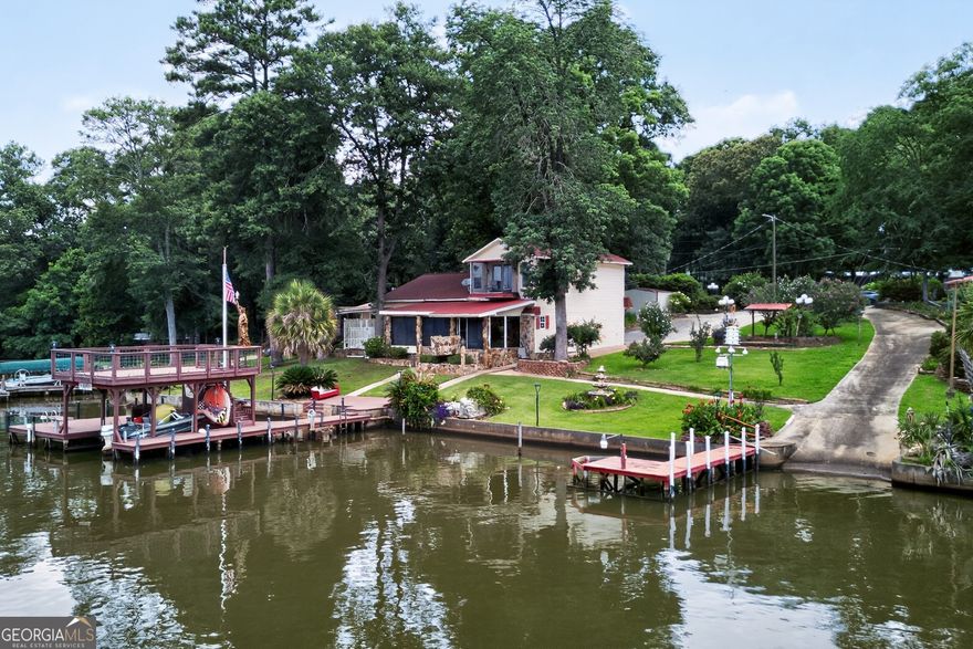 Welcome to your Lake Sinclair paradise! This beautifully updated 1,950+ sq ft home with an attached garage sits on a spacious double lot, offering the perfect lakefront living opportunity. Thoughtfully landscaped with stone accents, outdoor lighting, and walkways, the property also features a private boat ramp, a concrete seawall, and two docks-including a grandfathered two-story boathouse with a massive upper deck and 14+ feet of water depth at the end.  Enjoy sweeping lake views from the expansive 31' x 12' sunroom, complete with a hot tub-perfect for relaxing or entertaining year-round. Inside, the home has been tastefully renovated with new flooring, lighting, paint, appliances, countertops, and more. The open living space is perfect for family gatherings and offers a fresh and inviting atmosphere.   The entire second floor is dedicated to a luxurious primary suite, showcasing breathtaking 180-degree views of the lake. This serene space includes a private screened porch overlooking the water, a tray ceiling, space for a large walk-in closet and a generously sized en suite bath.  Whether you're looking for a full-time residence or a weekend retreat, this exceptional lakefront property is ready for you to start making new memories!