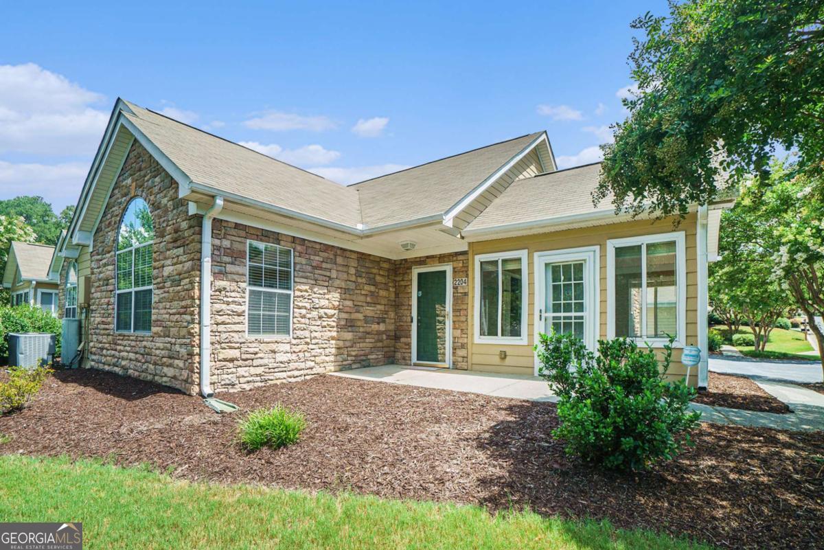 Discover easy, low-maintenance living in the highly sought-after Villas at Stone Mountain! This beautifully maintained 2-bedroom, 2-bath condo features a thoughtfully designed single-level layout and access to top-notch amenities, including a swimming pool, fitness center, and clubhouse. Ideally located just minutes from Stone Mountain Park and surrounded by a variety of shopping, dining, and everyday essentials, this home puts everything within easy reach. Inside, enjoy a spacious open-concept layout with soaring ceilings, a striking stone-faced fireplace, and a bright dining area that flows into the well-appointed kitchen. A sunroom with vaulted ceilings offers additional living space, perfect for reading, relaxing, or enjoying your morning coffee. The primary suite features a walk-in closet and a private bath with a step-in shower. The second bedroom also includes a walk-in closet-ideal for guests or a home office. A walk-in laundry room off the kitchen adds practicality and storage, while the attached 2-car garage enhances everyday convenience. Don't miss your chance to own this move-in ready gem in one of Stone Mountain's most welcoming and well-connected communities. Discounted rate options and no lender fee future refinancing may be available for qualified buyers.