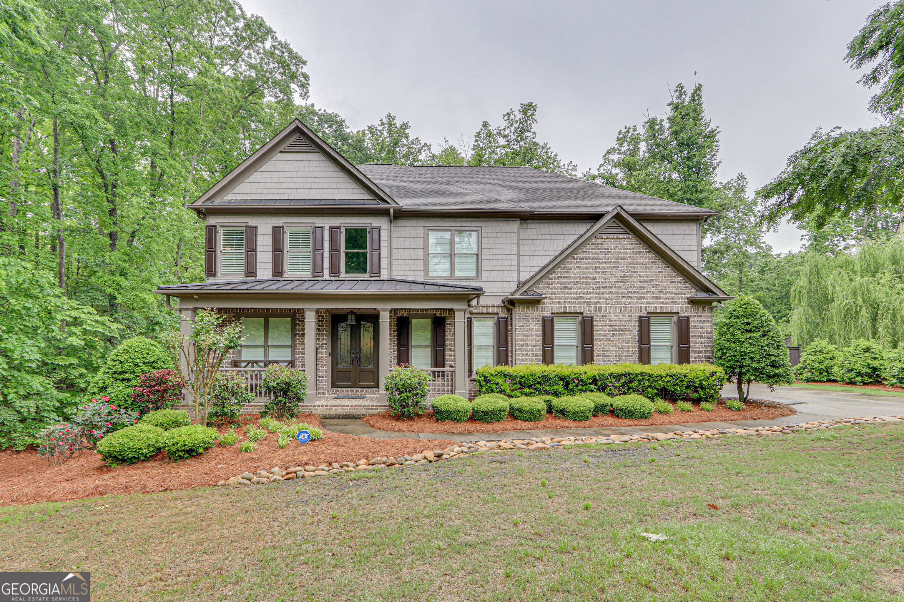 Seller is offering $10,000 toward buyer concessions-use it your way, whether that's closing costs, a rate buy-down, or a few personal touches to make the home your own! Nestled in the highly sought-after St. Michael's Bay swim/tennis community on Lake Lanier, this meticulously maintained 5-bedroom, 5-bathroom estate sits on 1.1 acre of beautifully landscaped grounds in a quiet cul-de-sac, bordering protected Corp property and zoned for East Forsyth High School. Built in 2016, this stunning home has been significantly upgraded with thoughtful enhancements throughout, including new tankless water heaters, custom iron front doors, and a fully finished basement. Inside, the home is a perfect blend of elegance and functionality. The kitchen boasts a large island with abundant storage, custom two-tone cabinetry, granite countertops, and high-end stainless-steel appliances, including a gas stove, oven, microwave, and dishwasher. A walk-in pantry with custom cabinetry and a butlerCOs pantry leads into a formal dining room, ideal for hosting. The family room features a wood-burning fireplace and a wall of windows, filling the space with natural light and offering picturesque views of the backyard. The main level also includes a flex office/bedroom with a full bath, perfect for guests or a home office. Upstairs, the expansive primary suite is a true retreat, complete with tray ceilings, a sitting area, and an oversized spa-like bathroom featuring his & her custom closets. Three additional bedrooms provide ample space, including one with a private en-suite bathroom and two connected by a Jack & Jill tiled bath. The laundry is conveniently located upstairs with thoughtfully planned custom cabinetry providing additional storage. The basement is an entertainerCOs dream, featuring an in-law suite, bedroom, bathroom, theater room, wine cellar, workout room, and a workshop with custom flooring. Additional home upgrades include a covered porch with beamed ceilings and shades, plantation shutters throughout, a new septic motor and riser for easy maintenance, and a large privacy fence enclosing the serene, flat backyard. Step outside into a park-like backyard, perfect for entertaining, relaxation, and play. Enjoy evenings around the fire pit, host gatherings on the expansive deck and covered porch, or simply take in the peaceful surroundings. Located within the gated St. MichaelCOs Bay community, residents enjoy tennis and pickleball courts, a pool, a playground, nature trails, and a community dock.