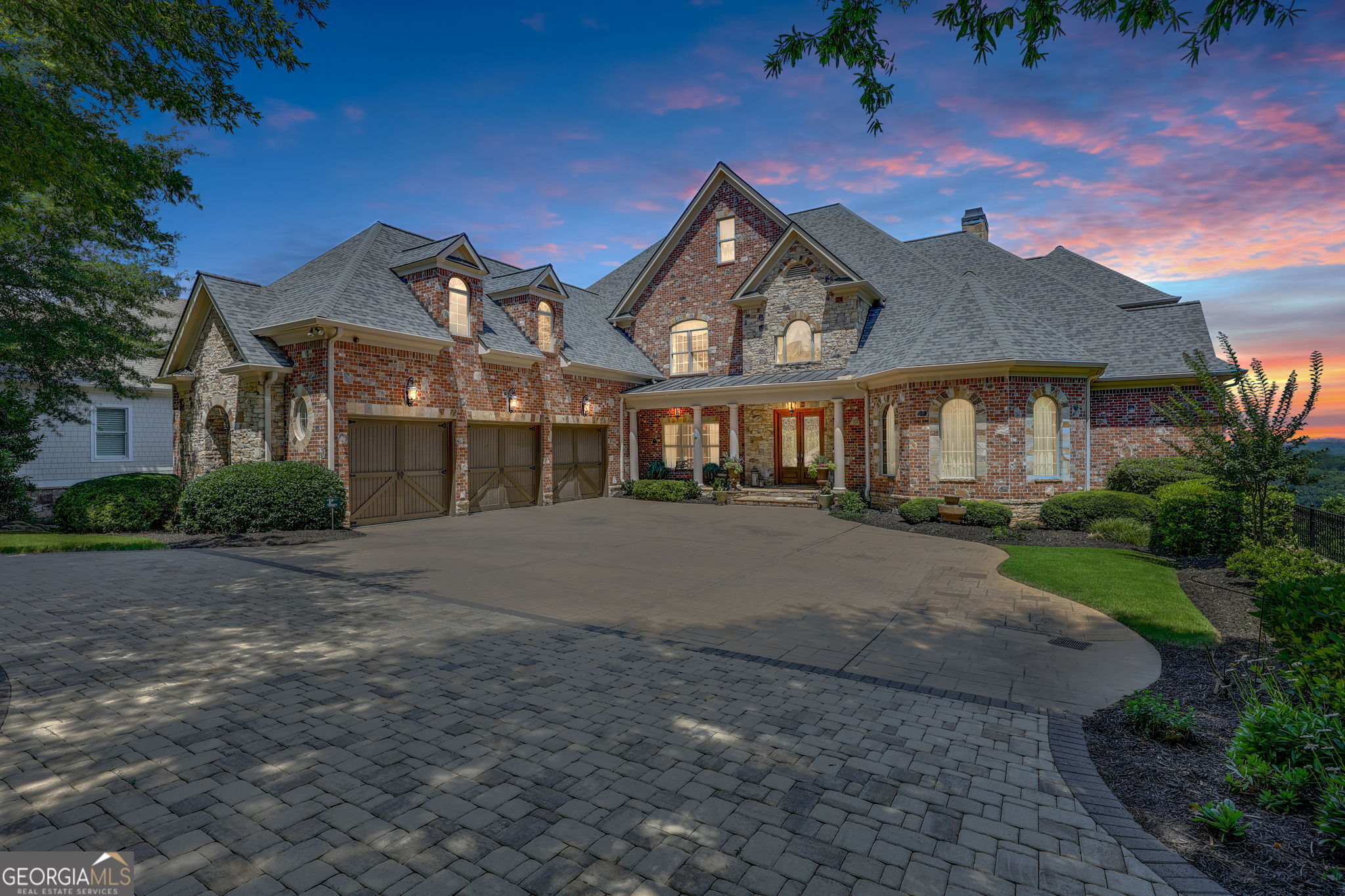 A rare opportunity to own a truly exceptional Lake Lanier estate, offered fully furnished with elegant, high-end pieces and ideally positioned on one of the most desirable lots on the lake. Located within the prestigious, gated Harbour Point Yacht Club and Marina community, this custom-built home showcases sweeping sunset views over Lake Lanier and the Blue Ridge Mountains from three expansive verandas. Designed with both luxury and lifestyle in mind, this four-level estate features an elevator, two home offices, and a heated pool and spa. A deeded boat slip is included, offering seamless access to lakefront living. The main level welcomes you with a grand two-story foyer and living room, formal study, and refined dining room. A brand-new custom chef's kitchen is outfitted with a 60" Wolf range with double ovens, Sub-Zero refrigerator, Miele coffee station, and an oversized walk-in pantry. The cozy keeping room features a stone fireplace, and the spacious primary suite includes a spa-like bath and newly designed California Closets. The terrace level is an entertainer's dream, complete with a wine cellar and tasting room, full kitchen and bar, gathering room with fireplace, 10-seat home theater, steam shower, sauna, and private guest suite. The lower poolside level adds even more space for entertaining with a second full kitchen, additional ensuite, gathering room, game room, and fitness room-all opening to the pool and landscaped, fenced backyard. Additional features include a three-car garage plus a dedicated Harley garage, a newly resurfaced pool with cabana, and numerous recent upgrades including a Crestron Smart Home system, updated irrigation, fire sprinkler and security systems, and tankless hot water.