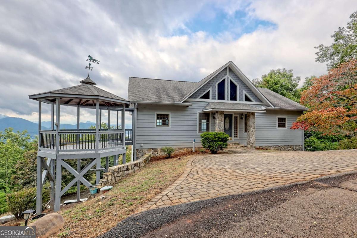 Breathtaking views abound from this 3-bedroom, 3.5-bath home on a 0.76-acre lot in the Mountain Harbor Community of Hayesville. The inviting wood beam living room with its striking tongue and groove ceiling and rich hardwood flooring sets a warm, welcoming tone, centered around a cozy double-sided gas fireplace. The main level also includes an outdoor dining gazebo, spacious kitchen, 1/2 bath, and the primary suite. Downstairs, there are 2 additional bedroom suites, each with its own private bath as well as a bar area and spacious living room. The bedroom and living areas each have access to the expansive covered deck. Recent improvements enhance both the interior and exterior, including a new HVAC system and refrigerator in 2023, along with exterior paint in 2022. Practicality meets style with durable Hardi plank siding, Pella inversion windows, Trex decking, and new exterior handrails and retractable screen doors added in 2021. The property is designed for both relaxation and potential, with a dedicated laundry room, a 2-car garage, and a basement already plumbed for an additional bathroom, all while providing a serene backdrop of unparalleled mountain and lake scenery. The Mountain Harbor Community offers an 18-hole golf course, clubhouse, fitness center, and pool area while being located just minutes from Lake Chatuge and many area attractions.
