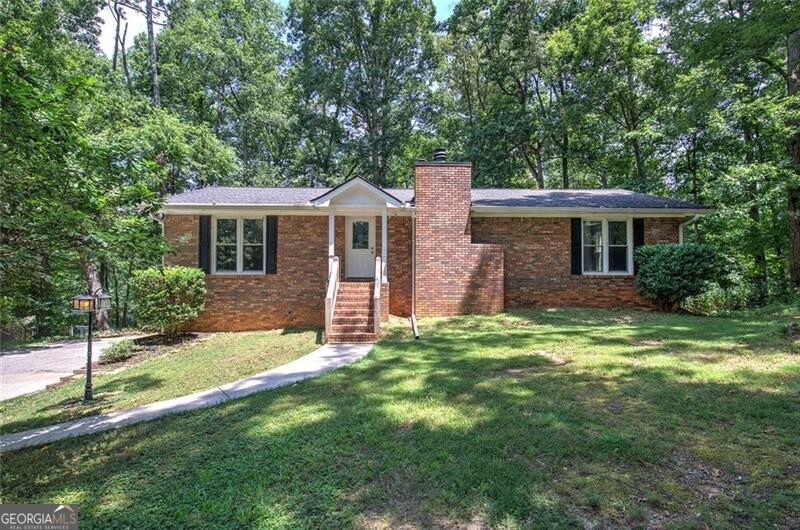 Location is everything in real estate and this home offers the best location! Enjoy a secluded wooded retreat on almost 2 acres in the heart of Austell. Fitness enthusiasts can walk, run or bike the Silver Comet Trail which is conveniently located right behind the property! Located just minutes from the East-West Connector with quick access to Cobb Hospital, shops like Home Depot/Lowe's & Walmart, dining, schools, golf & tennis facilities all within a couple of miles plus convenient access to Atlanta! This home itself is also a rare find- a 4-sided brick ranch with finished basement plus long driveway providing privacy from the street. Inside you will find a spacious family room with stately brick fireplace/accent wall which is open to the kitchen and dining area. Enjoy an on-trend kitchen with painted cabinets, timeless white appliances & plenty of cabinets & counter space. Retreat to the oversized owner's suite on main with large walk-in closet and ensuite bath. Two secondary bedrooms, one with a walk-in closet, are spacious and located on the opposite side of the home ensuring privacy. Enjoy additional living space in the finished daylight basement which offers a large rec room, full bath and additional finished room ideal for a home office, gym or storage. Neutral d cor throughout, this home is move-in ready! Enjoy the wooded views from the kitchen level deck with stairs to the yard or lower-level patio. The lot is long and narrow with a babbling creek tucked way back near the Silver Comet Trail. Septic pumped & inspected just 3 yrs ago. Other recent updates include a new breaker panel, new PEX plumbing throughout, double pane windows, new water heater 3 yrs ago. Other updates over the years include additional attic insulation, 30 yr architectural roof, gutters & HVAC. This home provides a neighborhood feel without the restrictions of a HOA. Plus, with major highways and public transportation, commuting to work or school is a breeze. Don't miss this amazing opportunity to own this low maintenance brick home in a prime location!