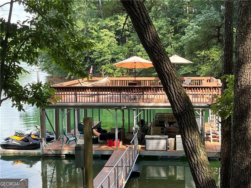 A VERY RARE FIND ON LAKE LANIER - This one of a kind lake front property features your own large private cove in Very Deep Water, isolated from the wind and in a no wake zone. No other dock can be permitted in the cove, so you will be able to enjoy complete privacy and peace. Come enjoy the most beautiful sunsets from your double slip dock with party deck that also comes with a permit to drive down to the lake. This house comes with two lots, just shy of an acre. The second lot is all grass and ready for any new addition to the house or leave as it is & have a great level play area. This Gorgeous ranch style home provides a full length porch on the front of the home & views of the Lake from both levels of the back of the home. It has been completely renovated with exposed beams, hardwoods throughout, phenomenal kitchen, bathrooms & finished daylight terrace level including your own bar. The Desirable Open Concept provides access to the screened porch and large deck on the main level allowing you additional space to entertain and enjoy the view & the finished daylight terrace level provides a large family/rec. room with custom bar, office, bedroom, full bath & exterior entrance which leads to the large covered patio, fire pit, lake & driveway areas. The detached garage was recently closed in and offers two parking spaces, one high enough to store a boat and two workshop/storage areas with garage door access to park a golf cart or ATV. Six additional parking spaces available on the parking pad next to the garage. If you enjoy entertaining this is a Must See! Located by the Six Mile Bridge, super close to GA 400, Publix & more! Call today to schedule your appointment to preview.