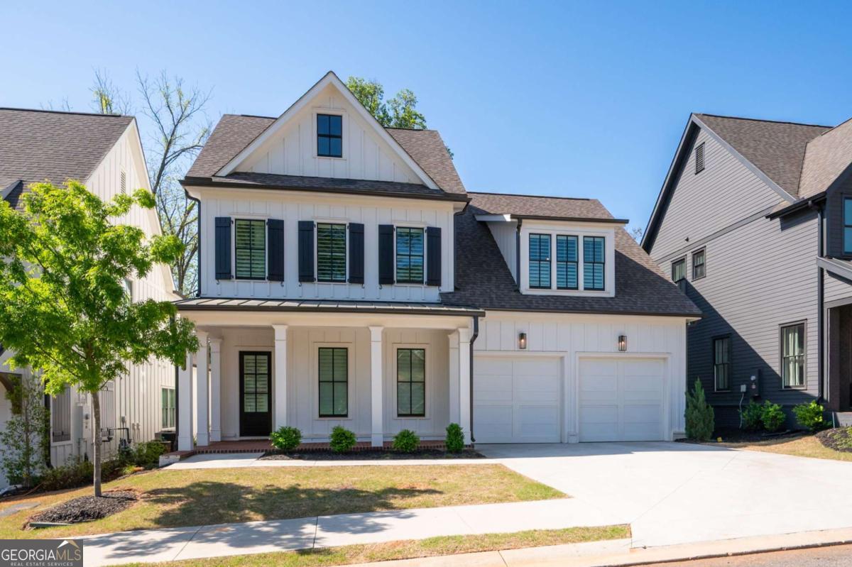 Stunning Modern Farmhouse in Prime Marietta Location! Welcome to 920 Wemberley Lane, a 5-bedroom, 5-bathroom luxury home in one of Marietta's most sought-after communities. Built in 2022 and purposefully upgraded, this like-new home offers sophisticated style and high-end finishes just minutes from Marietta Square and Kennesaw Mountain. Every element has been thoughtfully designed, from the charming covered front porch to the custom details inside. Step inside to discover high ceilings, deep baseboards, custom wood shutters, and modern light fixtures throughout. Hardwood floors create a seamless flow across the open-concept main level. The great room features a cozy fireplace with a shiplap surround. The show-stopping gourmet kitchen has a massive island with a breakfast bar, quartz countertops, top-of-the-line Jenn-Air appliances, a tile backsplash, floor-to-ceiling white cabinetry, and a butlers pantry with a wine fridge. A custom walk-in pantry provides ample storage, and the separate dining area is ideal for entertaining. A main-level guest bedroom and full bath offer flexibility for visitors or a home office. Upstairs, a loft area is perfect for a secondary family room or play space. The oversized primary suite is a true retreat, boasting a spa-like bathroom with a double vanity, soaking tub, and an expansive tile shower with dual shower heads. The custom walk-in closet is a dream, featuring built-in shelving and storage. Each of the three additional bedrooms includes its own ensuite bath and walk-in closet. The upstairs laundry room features a utility sink and extra storage space. Step outside through French doors to a large covered patio with an outdoor fireplace and a partially fenced backyard featuring upgraded turf-perfect for low-maintenance enjoyment. Community amenities include a greenspace, dog park, pavilion, and firepit. Zoned for award-winning Marietta City Schools, this home is conveniently located near parks, trails, and top-tier dining and shopping options. Luxury, comfort, and location-920 Wemberley Lane has it all.