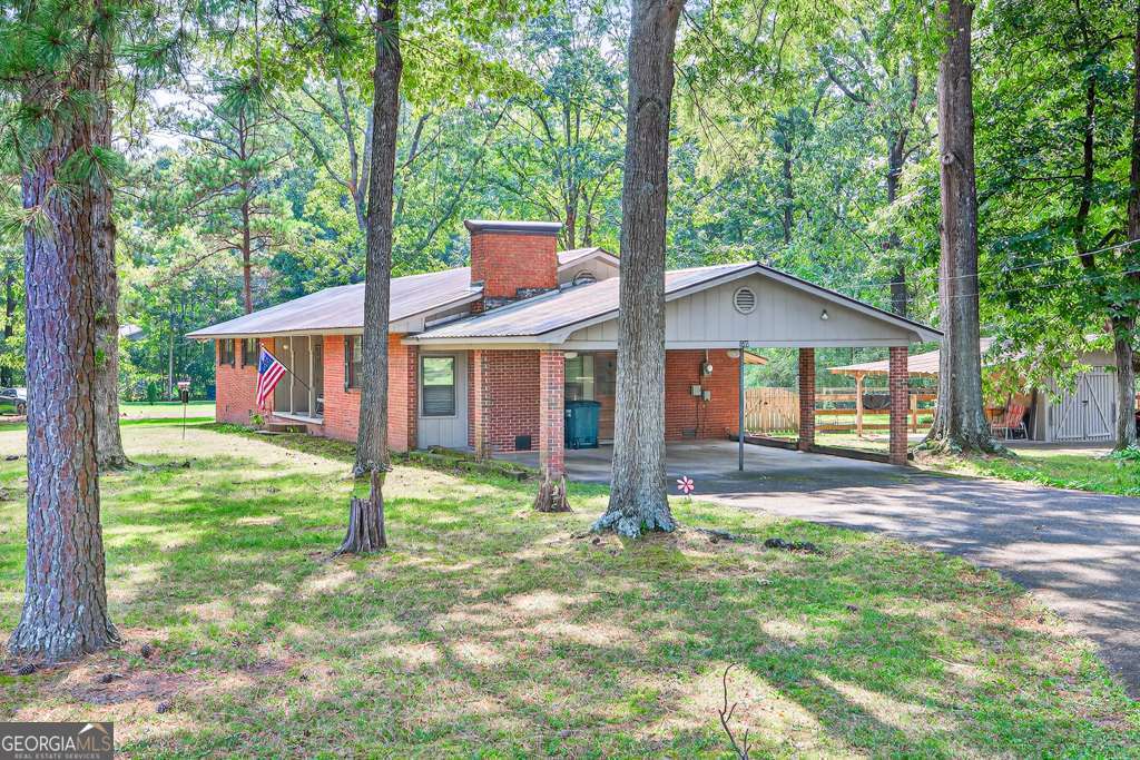 Set on nearly an acre (.94 acres across 2 lots) in an established neighborhood, this classic 4-sided brick ranch with a metal roof blends timeless character with thoughtful updates. Step inside from the 2-car carport, where a wood door accented with stained glass opens to the inviting interior. The spacious great room is anchored by a wood-burning fireplace with tiled ceilings and a small workshop. A separate front living room, filled with natural light, features an open concept living area and adds to the home's warm, welcoming feel. The kitchen has been beautifully remodeled and offers abundant cabinetry, a 4-burner gas range/oven. The adjacent laundry space adds everyday convenience. The large primary suite includes a luxurious private bath with a tile shower, while the secondary bedrooms share a hall bath with a touch of modern flair. At the back of the home, the sunroom (not counted in the square footage) provides a peaceful retreat with views of the level, fenced backyard, shaded by mature trees. A storage building with two lean-to shelters offers plenty of space for tools, hobbies, or outdoor equipment. Recent upgrades ensure peace of mind, including: Partial New Flooring New HVAC (12/2023) Freshly remodeled kitchen Septic cleaned, re-piped, and upgraded (2023-2024) Updated plumbing and electrical Three trees removed + limb trimming New backyard fencing With its generous parking area, this home is perfect for gatherings. All this comes with the convenience of being close to downtown Calhoun, schools, shopping, dining, and I-75 - and with no HOA fees.