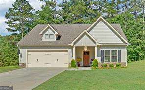 Experience the Charm of North Georgia Living! Discover this stunning, move-in ready ranch nestled in the heart of picturesque North Georgia. Featuring a highly desirable split-bedroom layout, the private owner's suite is tucked at the rear of the home, offering serene views of the lush tree line-a peaceful sanctuary away from the other bedrooms. With three bedrooms and two-and-a-half baths, the master suite impresses with spacious walk-in closets, a raised double vanity, and a luxurious separate tub and tile shower. Sunlight fills the open floor plan, highlighting granite countertops, custom cabinetry, and a large kitchen island, perfect for family gatherings or entertaining friends. Thoughtful upgrades throughout include a solid hardwood front door, ceiling fans, custom blinds, and luxury vinyl plank flooring in the main living areas, with soft carpet in the bedrooms for added comfort. Step outside to the covered back patio to enjoy morning coffee or evening relaxation, while the corner cul-de-sac lot, long driveway, two-car garage, and generous yard provide space, privacy, and convenience. Just minutes from downtown Dahlonega and Dawsonville, with easy access to dining, shopping, and the University of North Georgia, this home blends elegance, comfort, and modern convenience. A rare true North Georgia ranch, meticulously maintained and ready to welcome its next owner.