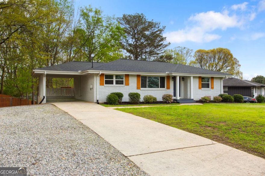 Welcome home to this beautifully renovated 3 bedroom, 2 bathroom ranch offering the perfect blend of modern upgrades and comfortable living. This single-level home features hardwoods throughout, a 2 year old architectural shingle roof, new windows, and upgraded lighting fixtures ensuring both style and efficiency. Head into the remodeled white kitchen, complete with granite countertops, a full wall accent backsplash, and stainless steel appliances. The kitchen island not only provides a convenient space for bar stools but also houses the washer and dryer units for space-saving convenience. There is ample space for a dining room table with views to the sunlight-soaked living room. The primary owner's suite boasts a renovated ensuite bathroom with accent tile and a standing shower. Two additional bedrooms complete the space along with a hallway bathroom with a modern soaking tub for a spa-like experience. Situated on a corner lot, this property features a back deck off the attached carport, offering easy access to the kitchen and outdoor living space. The fully-fenced backyard is perfect for entertaining or letting your furry friends roam freely! Just a short distance to top-rated schools, parks, Downtown Smyrna, the Silver Comet Trail, the Battery and major highwaysCa this home is truly move-in ready and has everything you could dream of in popular Smyrna!