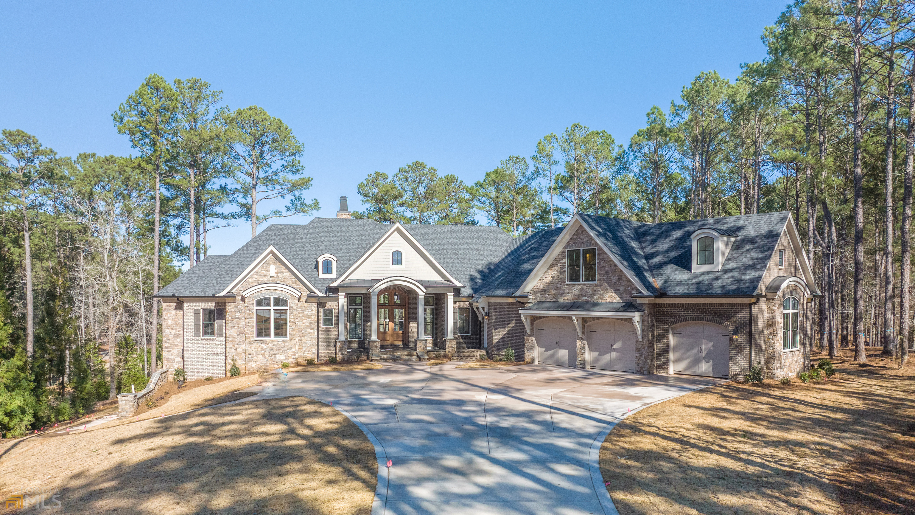 Elegantly and thoughtfully designed, new construction (to be complete Feb. 2023), custom masonry enclave built by Walden Signature Homes. This 5 en suite bedroom, 6.5 bathroom, 9,194 sqft home is located on the iconic 16th green of the Oconee Course at Reynolds Lake Oconee. Built to capture the privacy of the lot, expansive golf views from every room in the house, and placed on a corner lot oriented on the north/south axis for abundant sunlight that fills the property from every angle. The quality of construction and unique features are evident from the moment you step onto the flagstone detailed driveway. Walden Signature Homes are known for their custom stately trim packages, open sight lines, unique ceiling finishes and custom masonry exterior. Enter through the main level into the grand open floor plan shared between the living room, dining room, kitchen and keeping room with floor to ceiling, sliding doors across all 4 rooms with beautiful views of the 16th green and private pool. The main level Chefs kitchen includes beautiful custom cabinets, quartzite counter tops, 48in, 8 burner Wolf range with double oven, another separate Wolf double wall oven, and a side by side 36in Sub Zero fridge and 36in freezer. The butlers pantry is just off the kitchen and includes a wine fridge, ice maker, and additional dishwasher making this home an entertainers delight. The owners suite is on the main complete with breakfast bar, private sitting room with vaulted ceilings, fireplace, and large custom closets. Across the owners suite is a custom home library/office complete with custom paneled walls and tongue and grove ceilings with beams. There are 5 private en suite bedrooms throughout the 3 levels each thoughtfully designed for space, privacy and views. The lower level is complete with a second kitchen offering a Thermadore fridge, wine fridge and range, fireplace in family room, a second laundry room, home gym complete with wet steam room, workshop, theatre room and space for either an elevator to be installed or a wine cellar. A total of 6 fireplaces throughout the property including two outdoor fireplaces over looking the pool and spa. Make your way either from the screened terrace or lower level onto the pool deck with freeform pool and spa as you toast to the sunset overlooking one of Reynolds most envious golf views. Reynolds Lake Oconee- private waterfront community with Ritz-Carlton Hotel and spa, 6 golf courses, 11 refined restaurants, 3 Technogym fitness centers, 7 pools, on-site Spa and Sporting Grounds, 24hr security gate houses, and more. Seller makes Club membership available.