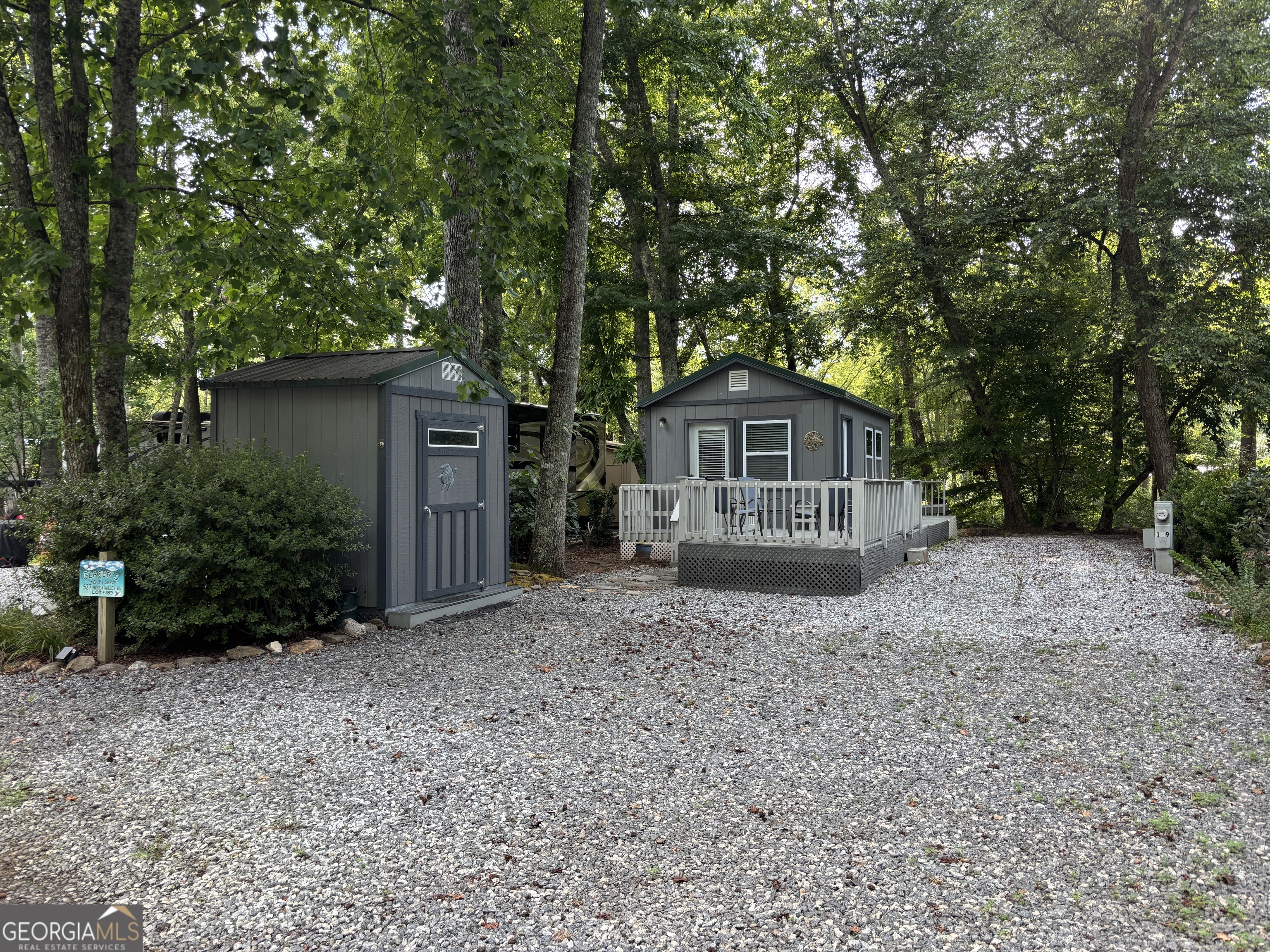 Discover a charming, tiny cabin (a perfect sidekick to your larger RV) with an unbeatable creekside view! If you're seeking a peaceful mountain getaway, this is the spot for you. Located in a gated vacation community in the North Georgia Mountains, this property offers a variety of amenities, including a pool, pavilion, clubhouse, and numerous planned activities. From the back porch, you'll find a stone patio complete with flagstone walkways and outdoor furniture that remains with the cabin. Enter the cabin through the front porch's retractable screen door, or enjoy a breeze from the back door's retractable screen as well. Inside, the cabin features wood-paneled walls and a vaulted wooden ceiling, creating a warm and inviting atmosphere. The kitchen is equipped with a full-size oven/range, dishwasher, microwave, lazy susan, double sink, and a breakfast bar with swivel stools. Cozy up to the fireplace while watching TV or relax in the updated full bathroom, which includes a shower and new PEX plumbing, as well as easy access from the outside. The fresh gravel driveway provides ample parking for a large motorhome or camper. The outbuilding offers plenty storage, cabinets, and space for tools, bikes, and other gear. Create lifelong memories here, whether you're relaxing by the firepit, fishing, or participating in community activities. The central location allows easy access to fun mountain towns and events, just minutes away from Cleveland, Helen, Dahlonega, Clarkesville, and Blairsville. Enjoy shopping, dining, fishing, hiking, and visiting local vineyards-the possibilities are endless! Please note that Paradise is a vacation resort community that does not permit full-time living. The listing agents are owners in Paradise, so feel free to reach out for a tour or more detailed information about Paradise and this property.