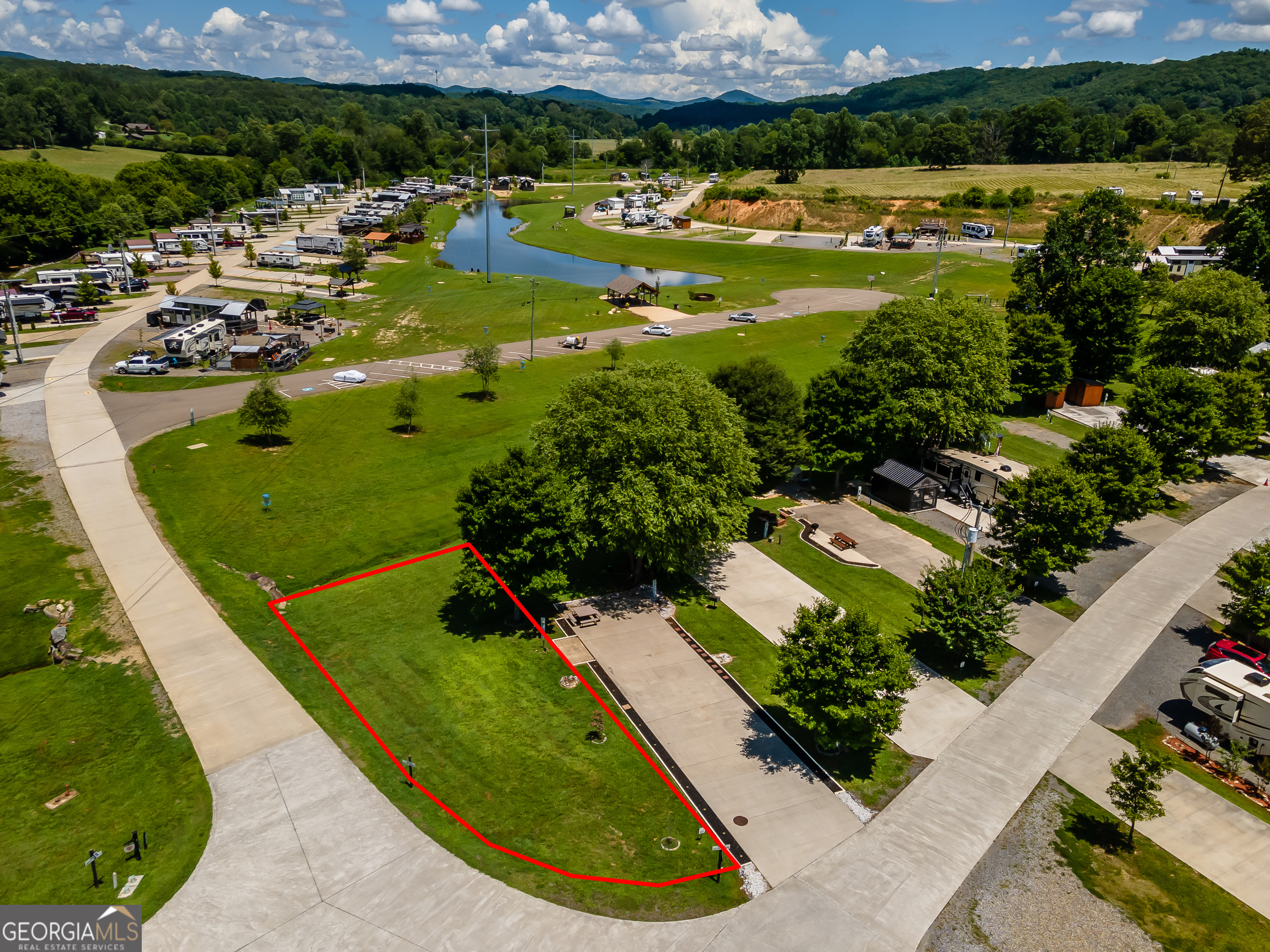 With featured community amenities such as: a dog park, several covered outdoor pavilions/picnic areas, an outdoor pool, restrooms and showers, a clubhouse, wood-fired pizza ovens, a playground, golf-cart rentals, 4 community fire pits, a gaga ball pit, outdoor basketball court, disc golf, picnic area, a stocked community lake, a 5br vacation home, tiny homes and RV's for nightly rentals, wi-fi and cable TV, laundry facilities and vending area--to name a few, in Waterside at Blue Ridge, boredom is a thing of the past! Alternatively, if you're looking for a peaceful, relaxing getaway, this community also masterfully delivers with well-kept grounds, posted community guidelines and speed limits, park rangers, gated entry, and homeowner's association. Now, let's talk about this amazing lot! Situated on a corner is lot #63--one of the only remaining privately held grassed lots in the community, leaving the end-buyer more autonomy as to whether to pave, place gravel, or keep as-is to enjoy the beautiful, soft and cushy, cool grass under your feet as you step out of your RV or camper. Perhaps your dream is to build a tiny home that you can stay in, either full-time or part-time, while bringing in short-term rental income when you're away, and if you choose not to build at all, with sewer, water, and power hook-ups, you can always rent out the lot! With Lake Blue Ridge located just 2.5 miles away, this community is conveniently located just far enough outside Metro Atlanta to where you feel like you're really "getting away" or going on a true camping trip, but close enough to "civilization" and downtown Blue Ridge where you can still go for a grocery run at Ingles, Aldi, or Food Lion; go to dinner at the highly rated Mike's Trackside BBQ, Boatdock Bar & Grill, or Southern Charm Restaurant; or go shopping at Wal-Mart, Roses, TJMaxx, or the Blue Ridge Mountain Mall. Schedule a showing today, reach out with any questions, and see yourself at Waterside at Blue Ridge--a lovely tiny home and RV park community with plenty to do, making it a perfect vacation and gathering spot for the entire family!
