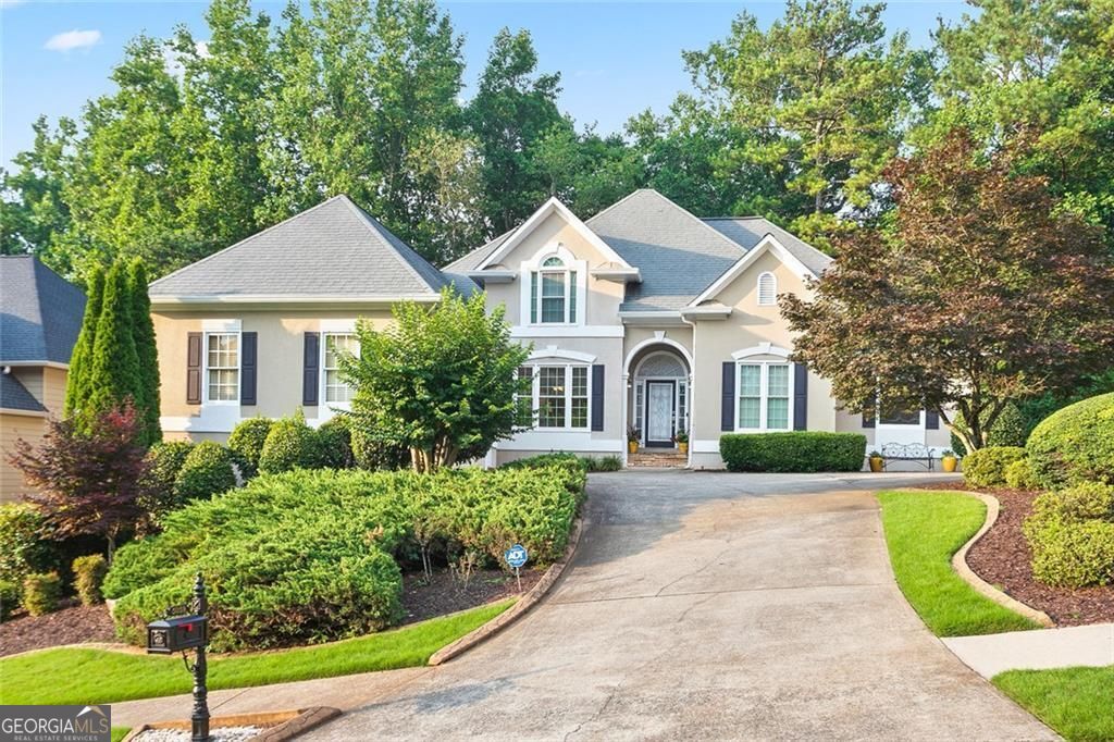 Price improvement in Towne Lake Hills East! Exceptional 5 bedroom 4 and 1/2 bath Featuring Master on Main and three beautifully finished levels! Enter the welcoming front courtyard driveway and you are greeted by the Flagstone front porch and the beautiful leaded glass front Door. The Tray Ceiling foyer is flanked by the open concept dining room with recessed accent lighting on the left and the Sitting room/office on the right! the gracious two story fireside great room reflects the style and function of this amazing residence. Light filled, spacious and peaceful describe the interior, complete with fresh paint, rich hardwoods and lush carpeting. This custom floor plan offers an elegant master suite on the main level with sumptuous bath and dual walk-in closets, and also two additional large main level bedrooms on the opposite side of the house that share a Jack and Jill full bath. The Chef's Kitchen includes gleaming white cabinetry, granite counters, stainless appliances, custom lighting, walk- in pantry with views to breakfast room and Great room. Completing the main level are the half bath and laundry room with Washer/Dryer included in the sale of the property. The upper level has two large bedrooms that share a bathroom each bedroom has it's own vanity! The wonderful daylight basement includes both finished and unfinished spaces. Finished rooms include Media/ Gathering room, Billiard/Rec room , full bath, flex bedroom/office room and kitchenette. Ideal for entertaining or teen/in-law suite. Unfinished area welcomes your completion with large rooms, or use for storage with high ceilings, and exterior entry door and full sized Boat door. Completing this amazing residence is the main level pergola deck overlooking the very private wooded backyard, Irrigation system, security system, and the spacious two car garage. With resort style amenities, 18 Hole Championship Golf Course, and The Tavern restaurant, Great schools, and close to Shopping, services, restaurants, parks and express lanes, and, Hospitals and also a short drive to trendy downtown Woodstock, 5059 Winding Hills Lane is the perfect spot for exceptional family living and entertaining!