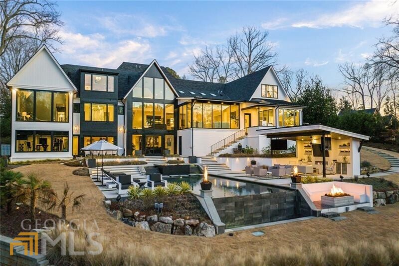 Situated on an incredible, gated golf course lot in the heart of East Cobb's Atlanta Country Club, this jaw-dropping Scandinavian-inspired modern masterpiece impresses with every turn. Enter through a large glass pivoting door into the two-story foyer, which offers a sightline of the award-winning backyard, infinity-edge pool, and outdoor living areas. Warm hardwood floors flow seamlessly into the two-story fireside great room where expansive sheets of glass frame the captivating golf course views. A beautiful backlit onyx bar area adds drama in the conversation area connecting the great room to the high-end modern kitchen. Sleek cabinetry, integrated appliances, quartz countertops with subtle veining and an island with a double waterfall edge work in tandem to create a magazine-worthy chef's paradise. Providing a more intimate space for everyday living, the adjacent family room and casual dining area boasts floor-to-ceiling windows and a wood-lined shed ceiling with Mid-Century-inspired beams. A scullery with a huge walk-in pantry is located off the kitchen alongside the gorgeous dining room with automated draperies and window shades. A glass-front temperature-controlled wine cellar adds visual interest to the open hallway off the sophisticated dining room. A conveniently located main-level laundry is accessed from the mudroom, as well as a built-in workstation and access to the three-car garage. Enrapture in the oversized main-level primary suite, offering cathedral ceilings, a large sitting area, motorized shades, and perimeter recessed lighting. Relax and unwind in the beautiful spa-inspired en suite bathroom, complete with separate vanities, separate water closets, a central seamless glass steam shower, a freestanding bathtub, heated floors, and an enviable custom-built closet. A luxurious guest suite, separate powder room, and a grilling porch complete the main level. Upstairs offers two impressive junior suites, each with sitting areas and luxury en suite bathrooms, a third en suite guest bedroom, and a landing area with morning bar. Perfect for entertaining, the living spaces continue on the terrace level, which includes a game area, recreation room, handsome bar, a theater, an office, a full bathroom, and a fitness studio. The walkout terrace level leads to the award-winning backyard, which is truly breathtaking. A sprawling terrace overlooks the spillover spa, infinity-edge pool, sundecks, cabana, fire pit, and golf course. Relax poolside under the covered cabana, complete with three mounted TVs and an outdoor fireplace flanked by refrigeration and storage. A sunken gas fire pit is surrounded by a built-in bench and overlooks the golf course as additional fire features add drama to the landscape. Vacation every day at 660 Atlanta Country Club Drive.