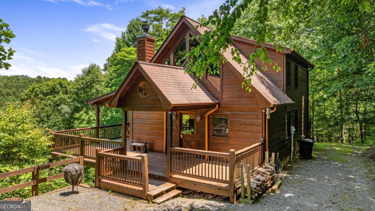 If you have "High Expectations", then this is the mountain getaway for you! You will be wowed by the magnificent long-range and close mountain views from multiple spots throughout. Featuring three levels with a bedroom and bath on each, along with loft living space and basement den/game room, this is the perfect layout for everyone to have their own space yet still be together. The spacious great room has a floor to ceiling custom stone, wood-burning fireplace, dining area, and kitchen with island seating and plenty of room for making culinary creations. The upstairs bedroom has its own private deck plus a soaking tub in the en suite bath. The lower floor features more lounging space perfect for movie watching, a pool table, foosball, and deck with hot tub to enjoy the magical views while you relax. Enjoy the babble of a small brook that runs along one side of the property. Finished with cozy wood throughout, rustic furnishings, and sold turn-key, you are ready for your private getaway or for use as an income-generating vacation rental. Located in the prestigious Mountain High subdivision with paved roads and underground utilities, you are in the middle of hiking, shopping, sightseeing, and more plus an easy drive to bustling Downtown Blue Ridge or Murphy, NC! Come see the home that will meet your "High Expectations" today!