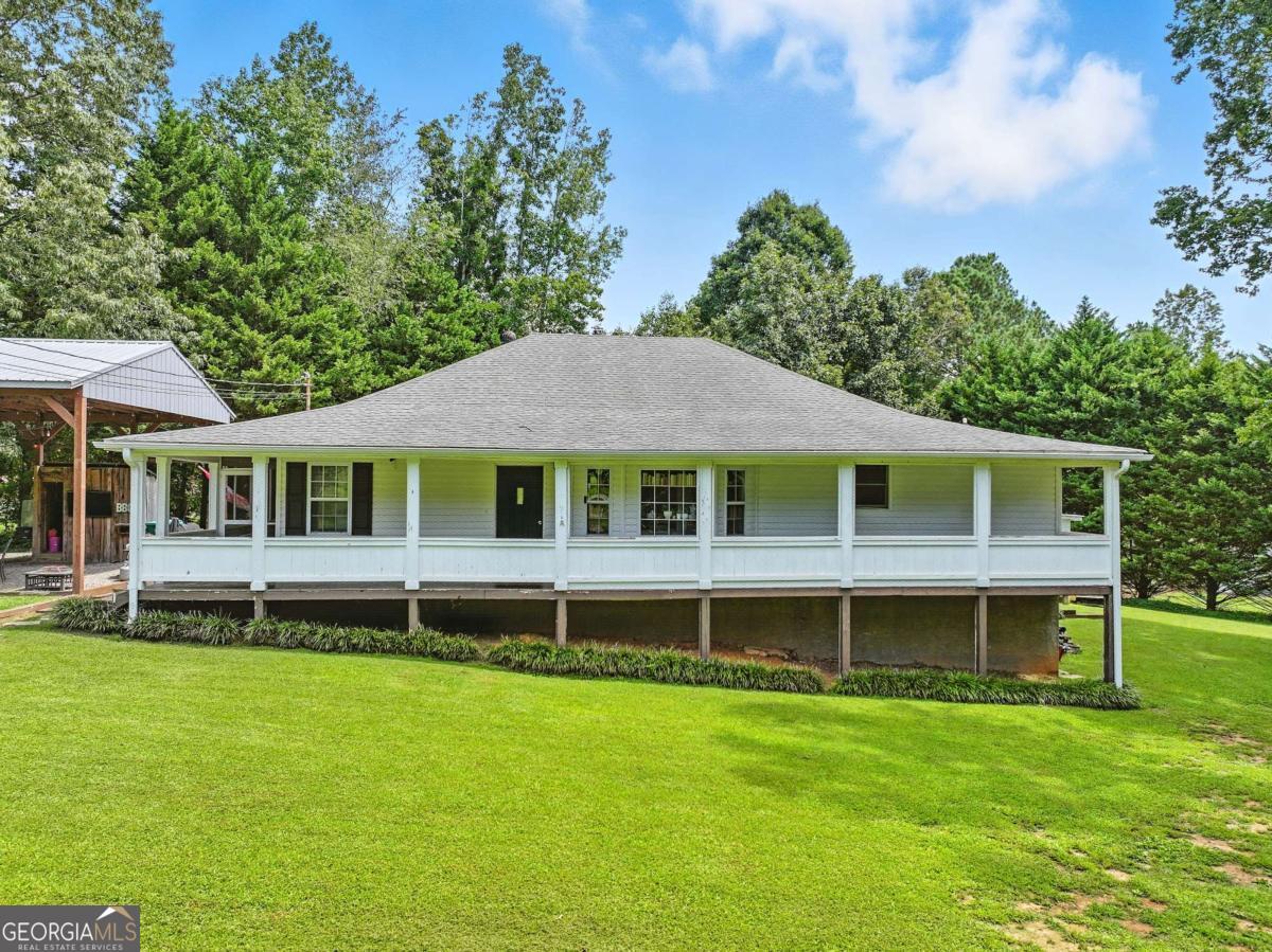 Charming Main Level Living with Wraparound Porch on 1.2 Acres. Welcome home to this inviting 3 bedroom, 2 bath raised ranch perfectly situated on 1.2 usable acres. A long circular drive leads you to a property full of possibilities, complete with a detached garage, pole barn, and plenty of extra parking for guests, RVs, or outdoor toys. The home itself is brimming with character - from the wide wraparound porch ideal for rocking chairs and morning coffee, to the rustic touches inside like wood floors, exposed beams, and custom details. The open kitchen and dining area is designed for gatherings, offering great natural light and a functional layout. Bonus rooms provide flexible space for a home office, playroom, or guest overflow. Outdoors, enjoy the covered pavilion that's perfect for entertaining, grilling, or simply relaxing while taking in the peaceful surroundings. With usable land, extra storage options, and room to spread out, this property is a rare find. Conveniently located yet offering the privacy of a country setting, this home combines charm, function, and space both inside and out. Don't miss the chance to make it yours!