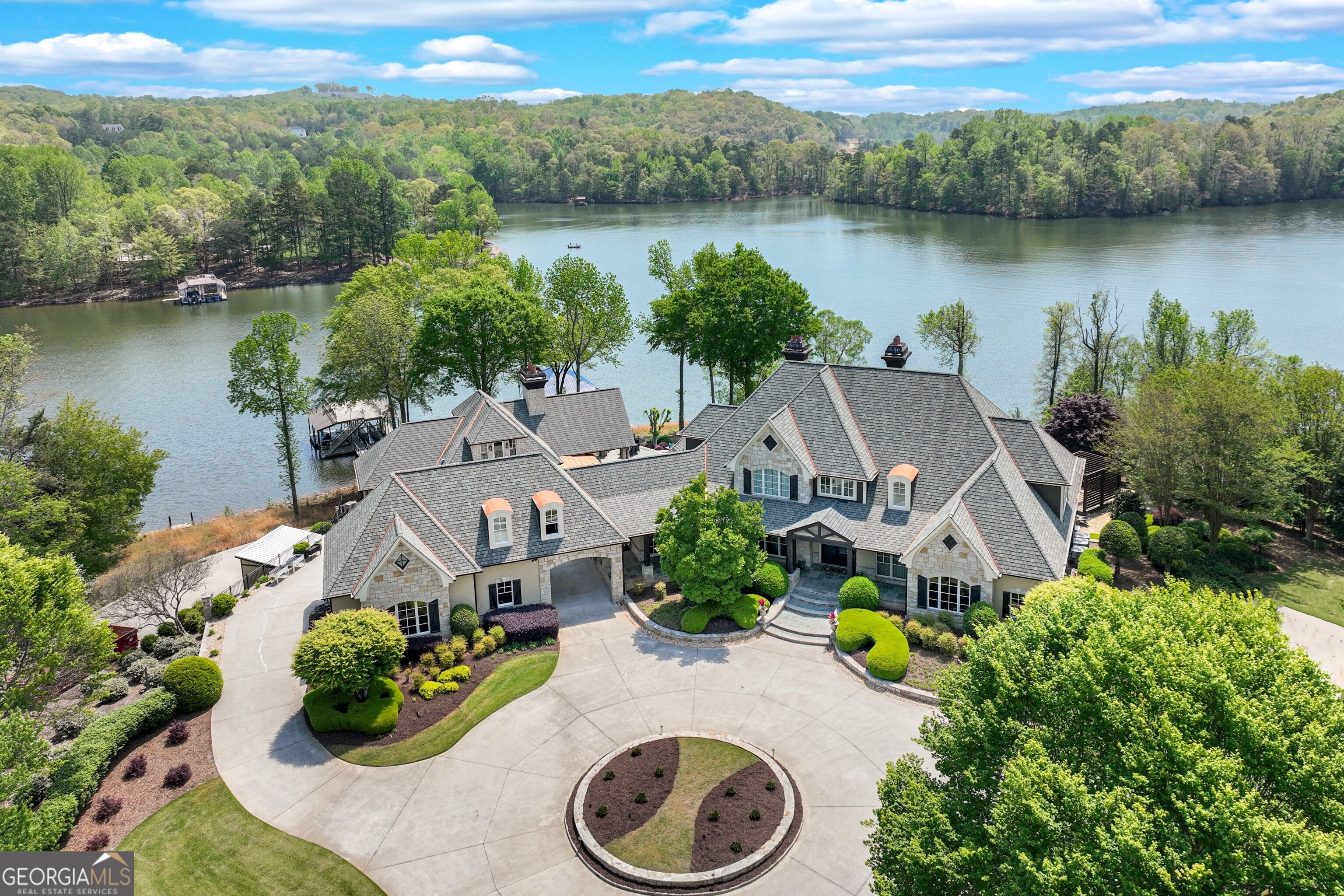 Welcome to an extraordinary waterfront estate on Lake Lanier! Situated within a private, gated setting, this exceptional property spans 4.38 acres and includes three lakefront lots, three private docks, and over 1,600 feet of riprapped shoreline, providing both breathtaking beauty and protection. With 270+ degree lake views from nearly every room, you'll experience the ultimate lakeside lifestyle in this remarkable estate! The custom-built main home has been recently updated and offers three finished levels of luxurious living. From multiple covered porches and patios to a sparkling saltwater pool and hot tub, this estate is ideal for entertaining or simply enjoying peaceful lake living. The chef's kitchen is a true standout, featuring dual islands, a Wolf gas range, Sub-Zero fridge, wine/beverage coolers, and a spacious caterer's pantry. The kitchen seamlessly connects to a sunny breakfast room and a vaulted gathering room with ceiling beams and a gas fireplace. A formal dining room with stone accents and a two-story great room with a grand fireplace add elegance to the space. A formal study has been transformed into a Bourbon Bar for this owner's enjoyment. The main-level primary suite is a true retreat with expansive lake views, a spa-inspired bath with a steam shower, soaking tub, double vanities, and two custom closets, including one that's over 600 sq ft, plus laundry room. Upstairs offers two guest suites with private bathrooms, as well as a cozy loft space perfect for a home office or reading/study area. The finished terrace level is designed with entertainment in mind. It features a full wet bar, a recreation and billiards room with a two-sided stone fireplace, a media room with custom seating and equipment, and a stunning wine cellar with tasting room. Two additional ensuites provide ample space for family and guests, and there's a large, unfinished storage or workshop area for added convenience. Step outside to the Pool House, an absolute highlight of this property, complete with a vaulted covered patio with a stone fireplace, an outdoor kitchen, and a fully-equipped indoor kitchen with stainless appliances and a large island. It opens to a warm and inviting family room with a fireplace, large pantry, and full bath. Above the Pool House is the Bunk House, currently used as a guest suite with a full bathroom and living area, offering additional versatility. Below the Pool House, there's 840 sq ft of unfinished space that can be used for a workshop, storage, or other personal needs. The property also includes a detached three-car garage with a charming carriage house above, which includes a full kitchen, living room, bedroom, bathroom, and laundry-ideal for guests or additional rental income. An additional one-car garage on the right side of the home provides even more space. This extraordinary estate is a rare find, offering privacy, luxury, and unmatched lake living. Located on the peaceful northeast side of Lake Lanier, just 10 minutes north of downtown Gainesville, The Chattahoochee Country Club, NEGA Medical and great public and private schools. Don't miss the opportunity to own one of the most unique and prestigious properties on Lake Lanier!