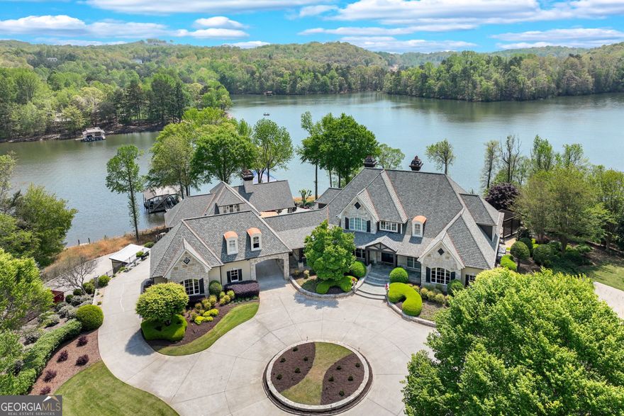Welcome to an extraordinary waterfront estate on Lake Lanier! Situated within a private, gated setting, this exceptional property spans 4.38  acres and includes three lakefront lots, three private docks, and over 1,600 feet of riprapped shoreline, providing both breathtaking beauty and protection. With 270+ degree lake views from nearly every room, you'll experience the ultimate lakeside lifestyle in this remarkable estate! The custom-built main home has been recently updated and offers three finished levels of luxurious living. From multiple covered porches and patios to a sparkling saltwater pool and hot tub, this estate is ideal for entertaining or simply enjoying peaceful lake living. The chef's kitchen is a true standout, featuring dual islands, a Wolf gas range, Sub-Zero fridge, wine/beverage coolers, and a spacious caterer's pantry. The kitchen seamlessly connects to a sunny breakfast room and a vaulted gathering room with ceiling beams and a gas fireplace. A formal dining room with stone accents and a two-story great room with a grand fireplace add elegance to the space.  A formal study has been transformed into a Bourbon Bar for this owner's enjoyment. The main-level primary suite is a true retreat with expansive lake views, a spa-inspired bath with a steam shower, soaking tub, double vanities, and two custom closets, including one that's over 600 sq ft, plus laundry room. Upstairs offers two guest suites with private bathrooms, as well as a cozy loft space perfect for a home office or reading/study area. The finished terrace level is designed with entertainment in mind. It features a full wet bar, a recreation and billiards room with a two-sided stone fireplace, a media room with custom seating and equipment, and a stunning wine cellar with tasting room. Two additional ensuites provide ample space for family and guests, and there's a large, unfinished storage or workshop area for added convenience. Step outside to the Pool House, an absolute highlight of this property, complete with a vaulted covered patio with a stone fireplace, an outdoor kitchen, and a fully-equipped indoor kitchen with stainless appliances and a large island. It opens to a warm and inviting family room with a fireplace, large pantry, and full bath. Above the Pool House is the Bunk House, currently used as a guest suite with a full bathroom and living area, offering additional versatility. Below the Pool House, there's 840  sq ft of unfinished space that can be used for a workshop, storage, or other personal needs. The property also includes a detached three-car garage with a charming carriage house above, which includes a full kitchen, living room, bedroom, bathroom, and laundry-ideal for guests or additional rental income. An additional one-car garage on the right side of the home provides even more space. This extraordinary estate is a rare find, offering privacy, luxury, and unmatched lake living. Located on the peaceful northeast side of Lake Lanier, just 10 minutes north of downtown Gainesville, The Chattahoochee Country Club,  NEGA Medical and great public and private schools.  Don't miss the opportunity to own one of the most unique and prestigious properties on Lake Lanier!