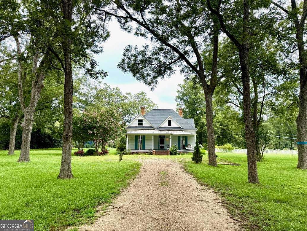 2.99% USDA ASSUMABLE LOAN - Rare Opportunity! Step into timeless Southern elegance with this beautiful historic home, perfectly situated on 2 park-like acres just minutes from Monroe and Madison, and less than 20 minutes from Watkinsville or Athens. With 4 bedrooms and 3 full baths, this home blends historic charm with modern comfort. Picture yourself relaxing on the oversized front porch or enjoying the view of blooming gardens that grace the property year-round. Inside, the main level boasts soaring 12' ceilings and original heart pine floors. The spacious eat-in kitchen features rich walnut-finished countertops, an open view to the family room, and is accented by crystal chandeliers and stained-glass windows for a truly one-of-a-kind dining experience. The main-floor primary suite offers a luxurious escape with a 5x5 frameless glass shower, classic clawfoot tub, and walk-in closet. Three additional bedrooms and a full bath are also on the main level. Upstairs, you'll find an additional room with an adjoining bath, a large den, and a versatile craft room. Step outside to a large back patio overlooking the picturesque yard - complete with a white picket fence enclosing one acre and a mature pecan orchard on the other. Recent upgrades include custom shades, tankless hot water heater, and upstairs HVAC (2019), plus all-new windows in the back addition. This open-concept yet historically rich property offers the perfect blend of warmth, character, and thoughtful updates - ready for its next chapter.