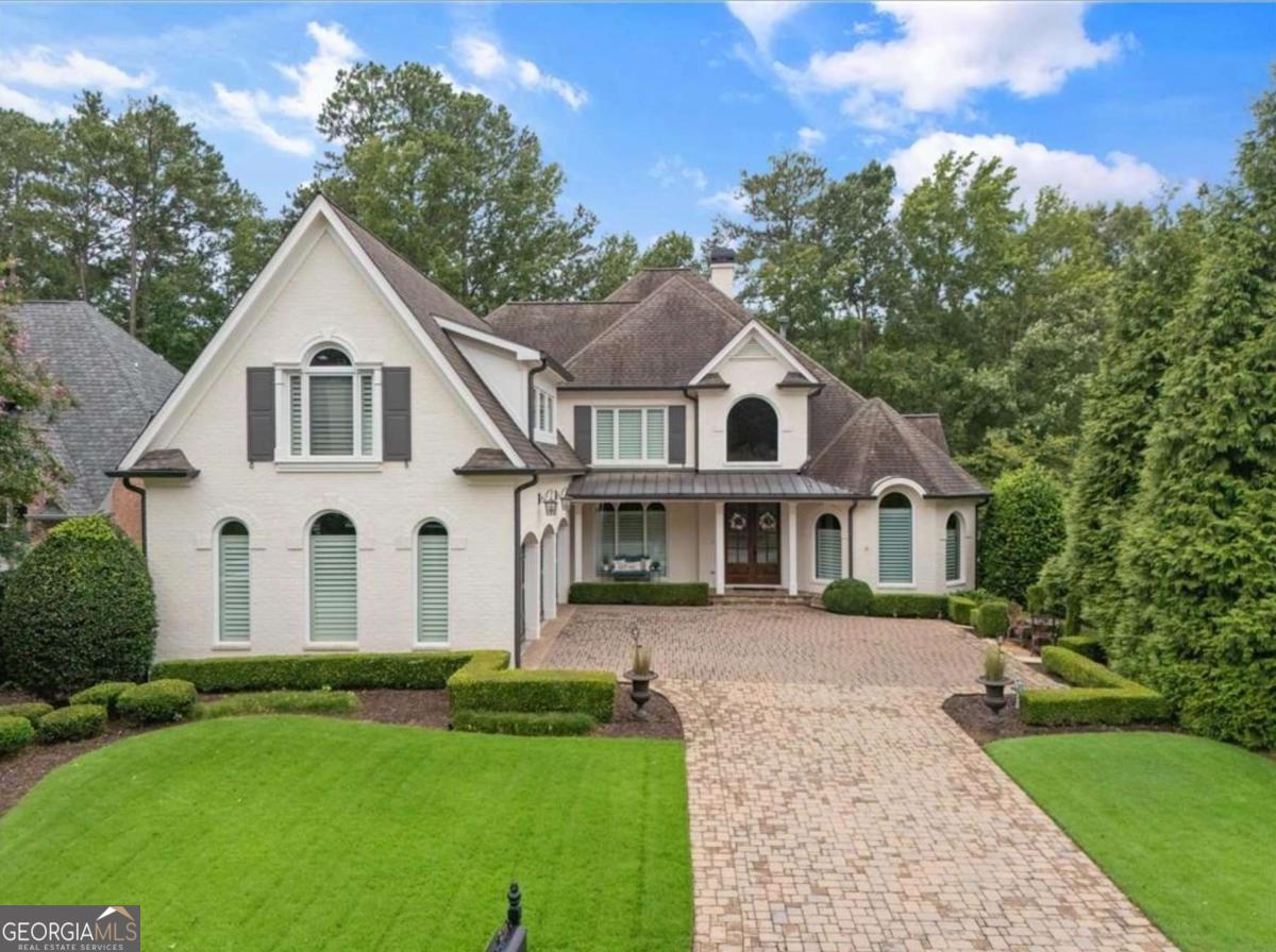 This timeless 4-sided brick estate blends classic architecture with today's most refined updates, all set on a beautifully landscaped lot with sweeping views of the 14th and 15th fairways of Country Club of the South. From the moment you arrive, the setting feels like a private retreat where every day begins and ends with resort-style views. A two-story foyer welcomes you with grand ceilings, streaming natural light, and the sparkle of brand-new Marvin windows and multiple French doors. The thoughtful floor plan transitions seamlessly between elegant entertaining spaces and relaxed everyday living. The heart of the home is the chef's kitchen featuring a spacious island with breakfast bar, custom cabinetry, and a perfect sightline into the vaulted fireside family room. Steps away, a richly appointed vaulted, wood-paneled office on the main level provides a private retreat for work or quiet study. The formal dining room sets the stage for memorable gatherings, while the main-level primary suite offers a peaceful escape with dual closets and a fully renovated spa bath. Upstairs, two generous ensuite bedrooms feature newly installed hardwoods, while the terrace level provides a private oversized suite with its own updated bath-perfect for in-laws, guests, or extended stays. In addition, the terrace level features spacious areas for TV and casual get-togethers, an exercise room, and approximately 1,000 square feet of unfinished storage space. Outdoors, manicured landscaping frames panoramic golf views, ideal for hosting friends or unwinding after a round. Practical updates abound: a three-car garage with new doors and an EV/RV hookup, smart thermostats, upgraded LED lighting, plus fresh paint throughout make this home truly move-in ready. Nestled within the gates of prestigious Country Club of the South, residents enjoy world-class amenities, top schools, and the security of one of North Atlanta's most desirable communities. This home is the perfect blend of timeless style, modern convenience, and an unmatched golf-course setting. Move in. Tee off. Live beautifully.