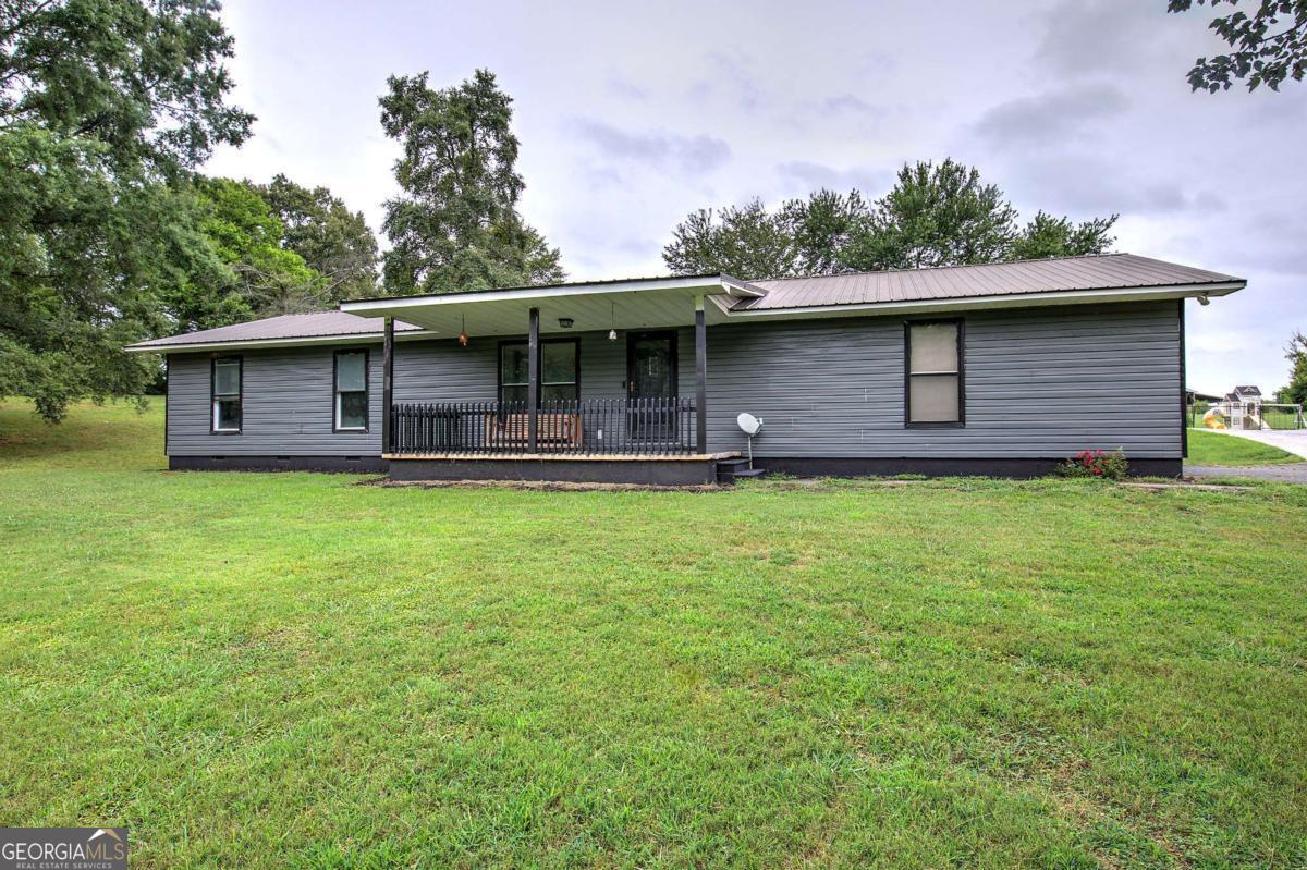 Welcome to 751 Liberty Road SW, this charming 3-bedroom, 2-bathroom ranch nestled on a picturesque 1.32-acre lot. This home offers a low-maintenance exterior with a durable metal roof, a spacious 2-car garage, an inviting rocking chair front porch, and a large back deck perfect for entertaining or relaxing outdoors. Inside, you'll find an open-concept layout featuring a cozy family room with a fireplace, a country-style eat-in kitchen, and a seamless flow into the dining and living areas. The beautifully maintained interior features luxury vinyl flooring throughout, complemented by neutral paint tones and recessed lighting in the main living areas. This inviting residence combines classic charm with modern comfort. The kitchen boasts ample counter and cabinet space, ideal for cooking and hosting. The primary suite is a peaceful retreat with a closet system, great for organization, and a luxurious tile rain shower in the ensuite bath. The property also boasts a detached 3-car workshop complete with power, water, a half bath, and two vehicle lifts - an ideal setup for mechanics or extra storage. Additionally, there's a 2-car attached garage attached to the home for everyday convenience. Located with easy access to both Calhoun and Rome via US-41 and I-75. Don't miss this rare opportunity to own a versatile, well-maintained home on over an acre of land with room to live, work, and grow. Whether you're looking to settle into peaceful country living or need the perfect setup for your projects and passions, 751 Liberty Road SW offers the space, functionality, and charm you've been searching for. Schedule your private showing today and come see why this property feels like home the moment you arrive!