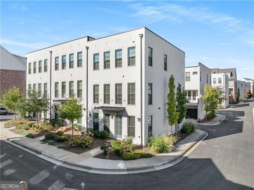 This thoughtfully curated End-unit Townhome blends modern design, architectural detail, and a vibrant walkable lifestyle in one of Alpharetta's most desirable communities. Every space has been enhanced with intention, creating a home that feels both sophisticated and welcoming. Natural light on every level.  The terrace level introduces a versatile ensuite bedroom featuring French doors, a walk-in closet, and a private bath with a tub/shower combination-perfect for guests, a private office, or a personal retreat. Entry from the terrace leads to a two-car garage that is as polished as the interiors, complete with epoxy flooring, a Tesla charging station, and overhead storage.  The main living level serves as the heart of the home, showcasing an open-concept design with wide-plank hardwood floors and ten-foot ceilings. The family room centers around a painted white brick feature wall with a sleek linear fireplace and dark cedar mantle, creating a warm and inviting focal point. The gourmet kitchen offers both beauty and functionality, highlighted by granite countertops, white cabinets extending to the ceiling, a built-in pantry, gas range with vent hood, and built-in microwave. The expansive island with counter seating, ideal for casual dining or entertaining guests. A covered deck extends off the kitchen and dining area, providing a seamless transition to outdoor living. A powder room with textured wallpaper adds a bold design statement on this level.  Upstairs, the primary suite exudes comfort and style, featuring two custom-built boutique-style closets and a spa-inspired ensuite bath complete with a rainfall showerhead, dual vanities, custom mirrors and white cabinetry. The secondary bedroom includes a custom feature wall, walk-in closet, and private ensuite bath, adding distinct character and dimension to the space. A laundry room is well located in the hall with full-size stackable washer/dryer with cabinets for storage offers both convenience and thoughtful design.  Throughout the home, recessed lighting, integrated surround sound, and designer finishes enhance the modern aesthetic. A custom staircase runner and cohesive design details bring a sense of refinement to every level.  Beyond the front door, the community offers resort-style amenities including a pool, clubhouse, fire pit and bocce court. Direct access to the Alpha Loop connects residents to Downtown Alpharetta and Avalon, where endless opportunities for shopping, dining, and entertainment await. Just steps away, The Maxwell District provides boutique shops and local favorites such as Rena's Italian Fishery, Fairway Social, and Lily Sushi Bar.  Blending timeless design with modern convenience, this townhome delivers not only a beautifully finished interior but also an unmatched lifestyle in Alpharetta's most vibrant destination. Top rated Milton HS and easy access to GA- 400