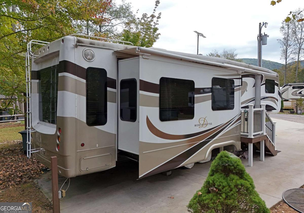 This VERY WELL MAINTAINED 1BR/1BA RV is perfectly situated at the end of the RV Park offering a peaceful CREEKFRONT setting with a view of the Pavilion. This RV features an open living room and kitchen area with stainless steel appliances. Nice size living room with an electric fireplace for cozy evenings. Step out onto the spacious deck to enjoy the tranquil sounds of the creek, making it an ideal spot for relaxation or entertaining. Outdoor building perfect for a craft room/workshop. Nestled in a small, intimate RV park, this property provides a serene retreat while being conveniently close to hiking trails, Vogel State Park and Brasstown Bald. This is an excellent opportunity for those seeking a quiet getaway in a scenic location.