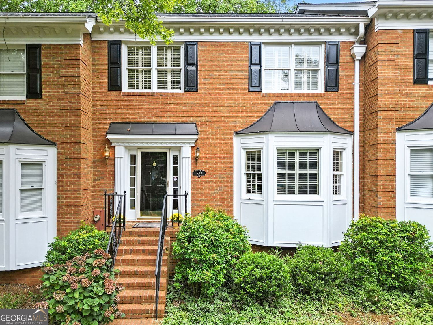 Brick elegance meets modern updates in this thoughtfully maintained three-bedroom, three-and-a-half-bath home with two spacious primary suites. The timeless exterior features stately black shutters, crisp white trim, and a welcoming brick stairway framed by lush landscaping, all while located in a quiet cul-de-sac surrounded by trees. Inside, the kitchen offers granite countertops, stainless steel appliances, and abundant cabinetry, plus a built-in desk for organization. A pass-through window connects the kitchen to the living space, making hosting effortless. The living room is anchored by a gas fireplace with a detailed mantel, flanked by built-in shelving, and illuminated by French doors leading to a bright sunroom with skylights. Hardwood floors and crown molding flow throughout the main level, while the finished basement provides fresh flooring, recessed lighting, and barn doors-ideal for a media room, home gym, or office. The fully renovated lower-level bath showcases a marble-topped vanity and a glass-enclosed shower with custom tilework. Upstairs, two primary bedroom suites offer generous layouts, walk-in closets and private baths. Additional features include a two-car garage with high ceilings and an abundance of storage. Enjoy a low-maintenance lifestyle with yard care and exterior upkeep covered by the homeowners association. The community pool is just steps away, and you're within walking distance to Dunwoody Country Club, coffee shops, groceries, restaurants, and more. Located in the high sought after Vanderlyn Elementary School District.