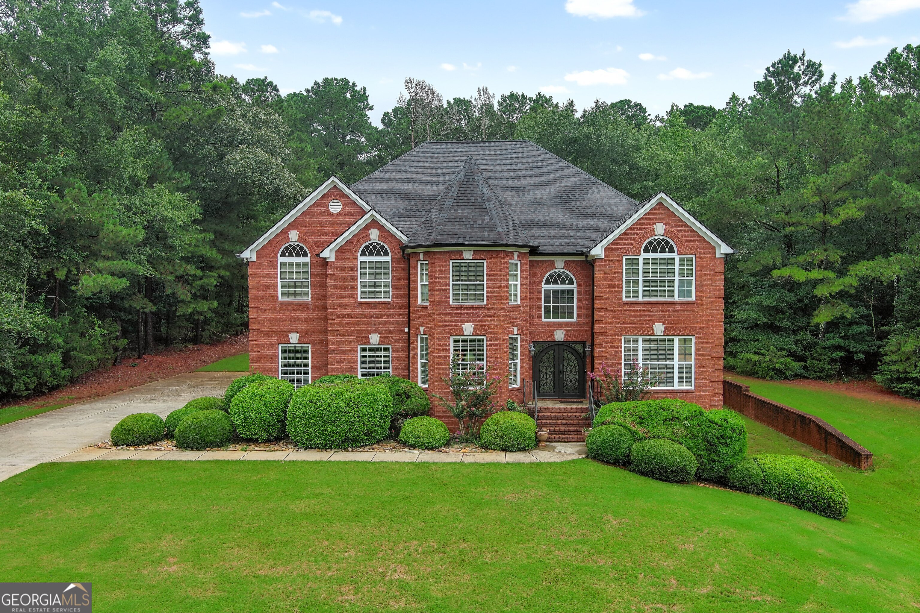 Welcome to your dream home-a stunning European Castle-style estate located in the prestigious "The Laurels" community of McDonough! This luxurious 4-sided brick home offers approximately 4,400 sq. ft. of main-level living space, with an additional 1,800 sq. ft. of upgraded finished basement. The basement features an exterior entry and is designed for exceptional entertaining. The grand entrance through beautiful wrought iron and glass double doors opens into a magnificent two-story foyer, setting the tone for elegance throughout. The highlight of this home is the massive great room with soaring ceilings and a dramatic oversized mirror above the fireplace, creating a sense of space, light, and sophistication. Boasting 6 spacious bedrooms and 4.5 bathrooms, including two oversized owner's suites-one on the main floor with a cozy fireplace and another upstairs-both complete with double vanities and separate tile showers, this home is perfect for multi-generational living or accommodating guests in style. The expansive family-style kitchen is a chef's dream with stainless steel appliances, abundant cabinetry, walk-in pantry, and a huge island that makes family gatherings and entertaining a breeze. A separate formal dining room, a breakfast area, and beautifully refinished tile bathrooms add to the home's elegance and function. Hardwood and carpet flooring throughout provide a warm and comfortable feel. The finished basement adds incredible value with ample space for recreation, movie nights, or even an in-law suite, while the exterior deck and lower-level patio are ideal for outdoor cookouts and entertaining. The home is set on a level backyard with a gently sloping front yard, adding charm and curb appeal. Located in a very safe, friendly neighborhood with wonderful neighbors, you'll also enjoy being in the highly sought-after Timber Ridge and Union Grove school districts. Just minutes from the vibrant McDonough Square, this home offers convenience, comfort, and character. We hope you feel the love, laughter, and joyful memories that have filled this home as you walk through it-and we can't wait for you to create your own.