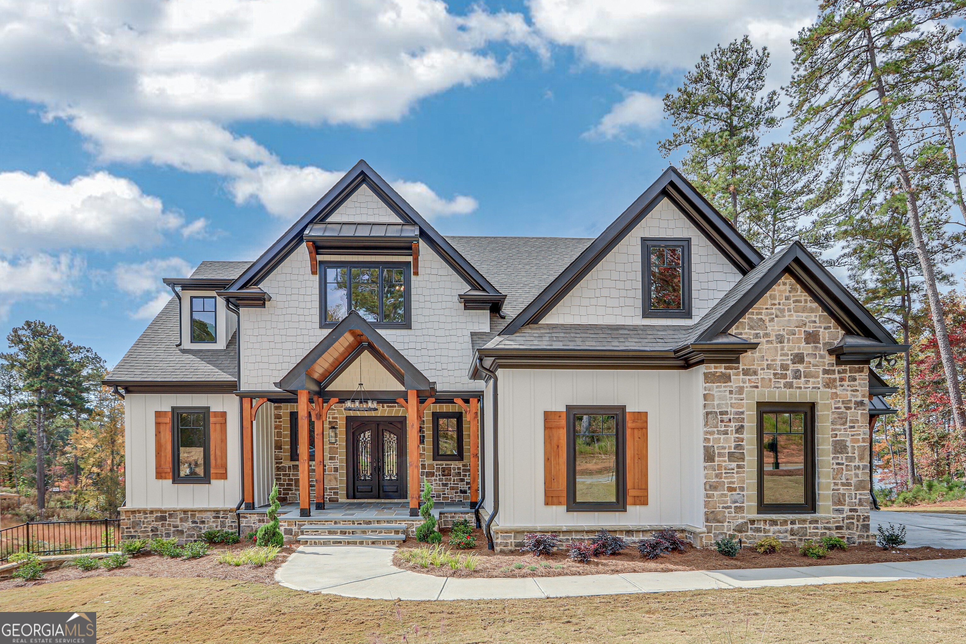 Welcome to new luxury lakefront construction in sought-after Cumberland on Lanier! Building is currently underway in the framing stage, this stunning modern farmhouse is being built on a rare gentle double lot with 1.18 acres and 250 feet of shoreline, complete with a brand-new Marine Specialties aluminum 32'x32' private double-slip Wahoo party dock in a quiet no-wake cove. Located in one of Gainesville's most desirable Lake Lanier communities, Cumberland on Lanier offers resort-style amenities including a sparkling pool, clubhouse, playground, two pickleball courts, and private gated access for peace and security. The lot is ideal for a future pool. You'll love the location-just minutes to Gainesville or Cumming, with easy access to Atlanta, top restaurants, and the lake's best marinas. Designed for lake life, this "elevator-ready" home features an open floor plan with over 1,950+/- square feet of covered outdoor living, a 4-car garage, and lake views through multi-paneled sliding doors. The exterior blends timeless style and low-maintenance materials including Pella windows, natural stone, cement siding, and stained wood accents. A vaulted screened porch with stone fireplace invites you to relax or entertain. Inside, the main level showcases a custom kitchen with waterfall-edge quartz island, designer cabinetry, wet bar, dining area, and grilling porch. The family room features a stone fireplace with built-ins and a vaulted tongue-and-groove ceiling. The main-level primary suite includes a tongue and groove vaulted ceiling, two walk-in custom closets,(one extra large with island with drawers) and private access to the screened porch. The spa-like bath offers heated tile floors, a freestanding tub, and a separate shower. A second ensuite bedroom or office with full bath, plus laundry and mudroom, complete the main floor. Upstairs, you'll find three more bedrooms with walk-in closets, (one a primary size with vaulted beamed ceilings), a finished bonus room, and two full baths. The unfinished terrace level features 12' ceilings and 2,400+/- sq ft for a future living area with a wet bar, guest suite, bath, bunk room, gym, or wine cellar, plus stubbed for two baths. A double door in the terrace level provides space for a future gold cart. Enjoy the easy walk or golf cart ride to your dock, or launch a kayak, paddleboard, or fishing line right from your shoreline. Built by trusted local builder ProStar Ventures, this home includes thoughtful upgrades like an irrigation system, and a whole house hot water recirculating system. Photos shown are of similar floor plans recently completed by ProStar Ventures.