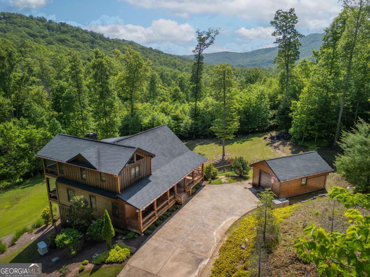 Welcome to your dream retreat in the serene Shepherds Ridge Subdivision! This exquisite 4-bedroom, 3.5-bathroom cabin, crafted by renowned builder Kevin Teague, offers an unparalleled blend of rustic charm and modern luxury. Nestled on a private 1.87-acre lot surrounded by mature vegetation, this home provides the perfect escape from the hustle and bustle of everyday life. As you arrive, you're greeted by an all-paved entry and a convenient concrete driveway leading to a one-car detached garage. The gently sloping, professionally landscaped yard is an oasis of tranquility, complete with a firepit for cozy evenings under the stars. Step inside to discover the open-concept main level, where the living, dining, and kitchen areas seamlessly flow together, perfect for entertaining. The living room is a showstopper, featuring a wall of windows that bathe the space in natural light and provide breathtaking views of the surrounding greenery and majestic mountains. Unique light fixtures and custom cabinetry add a touch of elegance and sophistication throughout. The main level also hosts a luxurious primary suite, while a second primary suite awaits on the upper level, offering flexibility and privacy for family and guests. The terrace level is a haven for relaxation and entertainment, boasting two additional bedrooms, a game room, a living room, a wet bar, and a patio that extends into the lush yard. Offered fully furnished and turn-key, this cabin is perfect for full-time living or as a weekend getaway. Enjoy the expansive wraparound porch, an ideal spot for morning coffee or evening gatherings, as you soak in the peaceful ambiance and stunning mountain views of this beautiful property. This cabin is not just a home; it's a lifestyle. Don't miss your chance to own this exceptional piece of paradise in Shepherds Ridge.