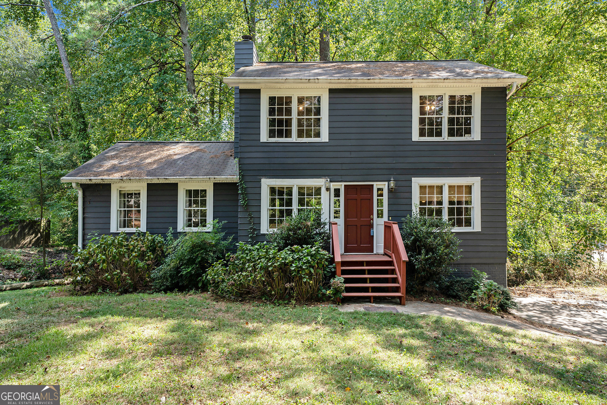 Build your own equity in Woodstock! The primary suite is located on the main level, and three secondary bedrooms share a bath on the upper level - a spacious home on a .6-acre lot, offering both privacy and room to grow. Located in the sought-after River Ridge High School District, this home is the perfect opportunity to renovate in an established area. Five minutes from Downtown Woodstock & easy access to North Fulton. Inside, the living room features a cozy stone fireplace, providing a warm and inviting gathering space. The main level boasts an open layout, with the potential to customize and make it your own. Step outside to enjoy the large deck, ideal for outdoor entertaining, while the partial basement and drive-under two-car garage offer extra storage and flexibility. With a little TLC, this home could truly shine. Create your dream space in a serene, wooded setting.