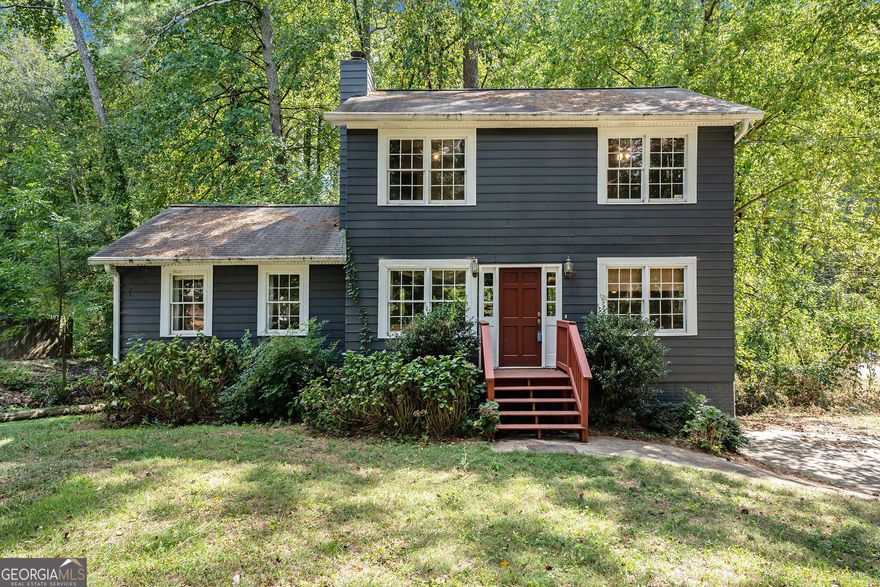 Build your own equity in Woodstock! The primary suite is located on the main level, and three secondary bedrooms share a bath on the upper level - a spacious home on a .6-acre lot, offering both privacy and room to grow. Located in the sought-after River Ridge High School District, this home is the perfect opportunity to renovate in an established area. Five minutes from Downtown Woodstock & easy access to North Fulton. Inside, the living room features a cozy stone fireplace, providing a warm and inviting gathering space. The main level boasts an open layout, with the potential to customize and make it your own. Step outside to enjoy the large deck, ideal for outdoor entertaining, while the partial basement and drive-under two-car garage offer extra storage and flexibility. With a little TLC, this home could truly shine. Create your dream space in a serene, wooded setting.