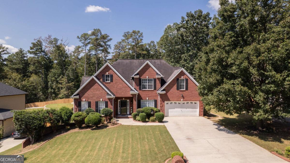 Nestled on a beautifully landscaped lot in the sought-after Slater Mill Plantation subdivision, this stately brick-front traditional home offers an exceptional living experience. Step inside through the private front entry into a dramatic two-story foyer that flows seamlessly into a stunning open-concept family room. This inviting centerpiece of the home is anchored by a cozy fireplace and features beautiful hardwood floors. The adjacent spacious kitchen is perfect for both everyday living and entertaining, equipped with a stone backsplash, a pantry, and a bright breakfast area. The main level also hosts the serene primary suite, a true retreat featuring a comfortable sitting area and a large en-suite bathroom. The spa-like bath is appointed with a double vanity, a separate tub and shower, and a spacious walk-in closet. A dramatic stairway leads to the upper level, where three private bedroom suites await. The home's living space is further extended in the fully finished basement, which includes an additional bedroom, a full bath, and a versatile flex room with a walk-in closet. With both interior and exterior entry points, this level offers fantastic potential for an in-law suite, media room, or guest quarters. Enjoy the outdoors from the deck, which overlooks the private, wood-fenced backyard. This home features an attached two-car garage with a level driveway. Residents enjoy wonderful community amenities, including a swimming pool, tennis courts, and sidewalks. This immaculately maintained six-bedroom, 3.5-bath residence is a rare find.