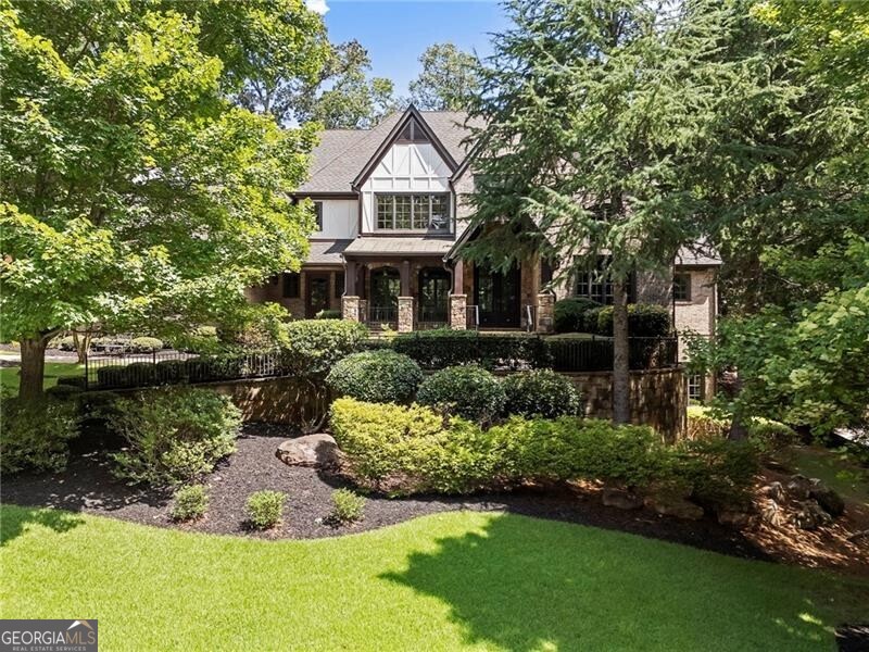 Experience the perfect blend of timeless sophistication and relaxed luxury in this extraordinary residence, nestled within the prestigious gated golf community of The River Club. Ideally located just a short walk from both the clubhouse and the lakeside family center, this home offers effortless access to world-class amenities that define this exclusive enclave. This premium homesite is one-of-a-kind-offering serene privacy and picturesque views from every angle. From its classic architecture to the impeccable finishes found throughout all three levels, every detail of this home exudes enduring quality and thoughtful design. Whether you're hosting elegant dinner parties, casual gatherings with friends, or enjoying quiet moments with family, this home provides the ideal backdrop for every occasion. Tucked away behind lush landscaping, the front porch is where evenings are spent watching the sunset and greeting neighbors walking by in the distance. The warm and welcoming foyer leads to richly appointed living spaces. A handsome study with fireplace, exquisite millwork, and sun-filled window creates the perfect setting for a home office. The formal dining room flows to a gracious great room featuring a limestone fireplace, coffered ceilings, and stunning views of the beautifully landscaped backyard and tranquil waterfall. Unique to this home is the charming "friends and family entrance," which opens into a well-appointed service area-ideal for welcoming guests with refreshments upon arrival or serving cocktails adjacent to the dining room when hosting formal parties. The gourmet kitchen, centered around a spacious island, flows effortlessly into the vaulted keeping room with an oversized, striking stone fireplace. Beyond the keeping and breakfast rooms, is one of the areas you will enjoy the most, especially in the fall! The cozy screened porch with beautiful wood burning fireplace opens to the grilling deck and overlooks the waterfall. This lot also offers the coveted "best of both worlds" in that you walk out the main level to the screened porch, grilling station, and level backyard, with the lower level just outside the terrace level being pool ready. On the terrace level, step into the ultimate haven for hosting and relaxation-where exquisite stonework and rich millwork set an unforgettable tone. The showstopping centerpiece is a stunning, stone-wrapped English-style pub, complete with a private gentleman's room and wine cellar with hidden enclave for storing valuables. Whether you're enjoying fireside conversations, movie nights in your private home theater, or friendly competition in the billiard room, this luxurious terrace level delivers unforgettable moments and endless entertainment. A rare and highly sought-after feature in this home is the inclusion of two luxurious primary suites-one conveniently located on the main level and another upstairs. The home is also elevator-ready for added ease and accessibility. The home offers 7 spacious bedrooms, including 5 ensuite bedrooms, a large bonus room with built-in study/office area, and 2 additional bedrooms on the terrace level. Lovingly maintained by its original owners, this timeless home has recently been refreshed with new paint, new carpet, and refinished hardwood floors, making it truly move-in ready. Set along the iconic Chattahoochee River, The River Club is a certified Audubon Sanctuary and one of the Southeast's premier private communities. Residents enjoy a wealth of amenities including a Greg Norman-designed championship golf course, a lakeside family sports center featuring both clay and hard-surface tennis courts, a junior Olympic lap pool with splash pad and slide, and a state-of-the-art fitness center. Dining options abound, from casual fare to fine dining. With 24/7 gated security, top-rated schools, and close proximity to upscale shopping, dining, and cultural attractions, The River Club offers a lifestyle of unmatched luxury and convenience.