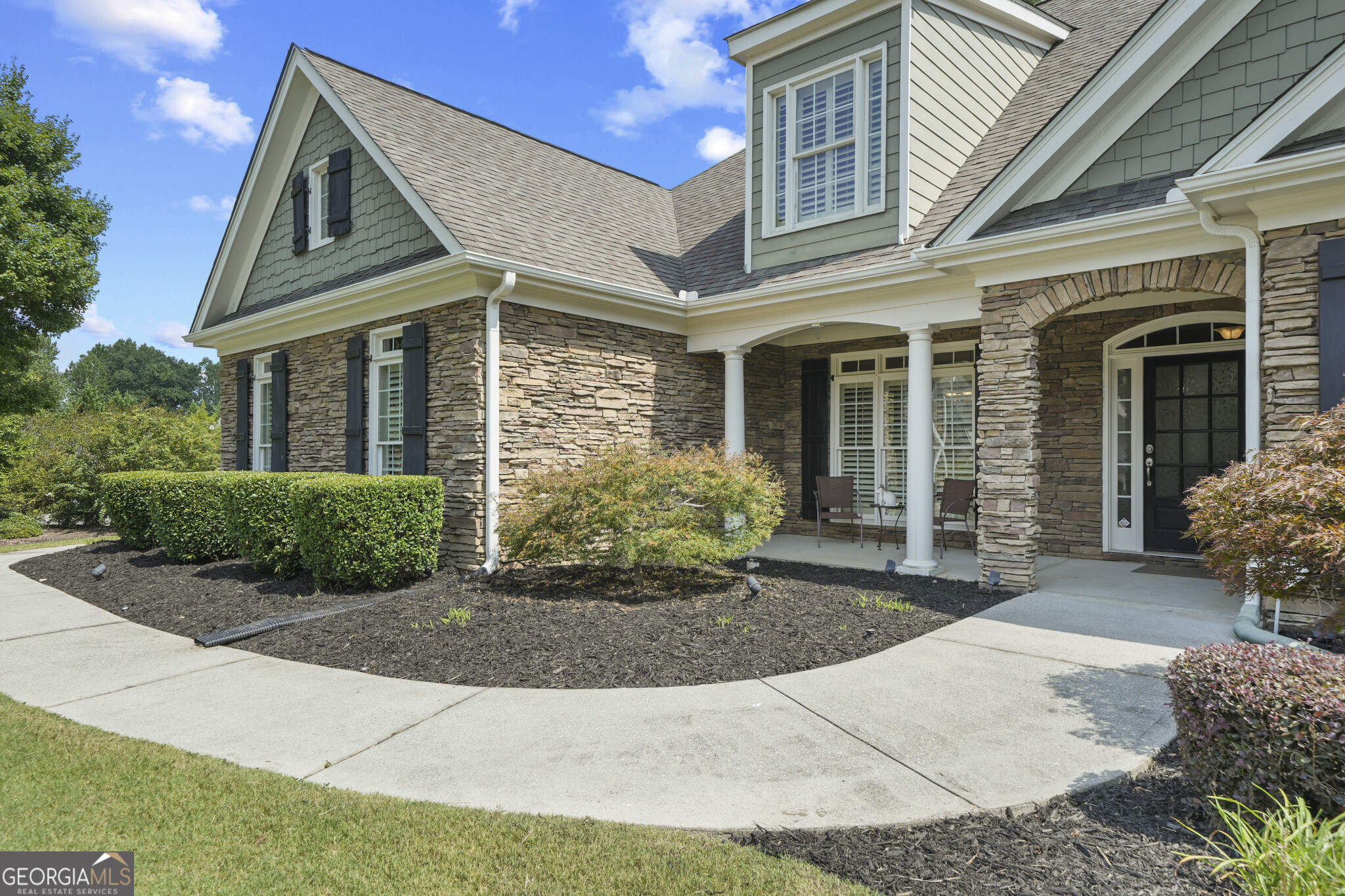 This beautiful 5-bedroom, 4-bath craftsman RANCH is perfectly situated on a spacious corner lot just outside Lawrenceville, offering the ideal balance of privacy, charm, and convenience including energy efficient upgrades such as a NEW HOT WATER HEATER AND 2 HVAC SYSTEMS. Featuring stacked stone accents, a two-car side-facing carriage-style garage with an epoxy floor, and professional landscaping maintained by an irrigation system, this home boasts year-round curb appeal. Architectural lighting creates a striking evening ambiance that highlights its timeless design. Located in a vibrant community, you'll enjoy resort-style amenities including a large clubhouse, lap pool with a slide, shallow swim area for little swimmers, tennis courts, playground, and more. The area offers plenty of conveniences, with grocery stores, shopping, dining, health care, and reputable schools nearby, plus access to Tribble Mill and Bay Creek Parks for all your outdoor activities. Step inside to a covered front porch that opens to a detailed foyer with tray ceilings, flanked by a formal dining room and office, both featuring tray ceilings, transom windows, and plantation shutters for added elegance. Rich hardwoods and crown molding lead into the open family room, highlighted by coffered ceilings and a cozy stacked stone fireplace. The spacious eat-in kitchen is a chef's dream with granite countertops, travertine backsplash, breakfast bar, stainless steel appliances including a wall oven, and a seamless flow into the dining room for effortless entertaining. The adjoining keeping room provides direct access to the patio for ideal indoor-outdoor living. The main-level primary suite is a private retreat, featuring a spa-like bathroom with double vanity, travertine-tiled jetted tub, and walk-in shower. Three additional secondary bedrooms and two full baths complete the main floor. Upstairs, you'll find a versatile en-suite bonus room perfect for guests, a media room, playroom, or entertainment space. The options are endless! The backyard features a patio with a built-in gas line, ideal for creating your dream outdoor cooking area. The tree-lined backdrop provides added privacy, making it perfect for relaxing or entertaining. Every detail of this home has been thoughtfully designed with a list of upgrades to deliver a lifestyle of comfort and luxury. Don't miss the opportunity to own this incredible home in a sought-after location close to everything, yet tucked away from the hustle and bustle.
