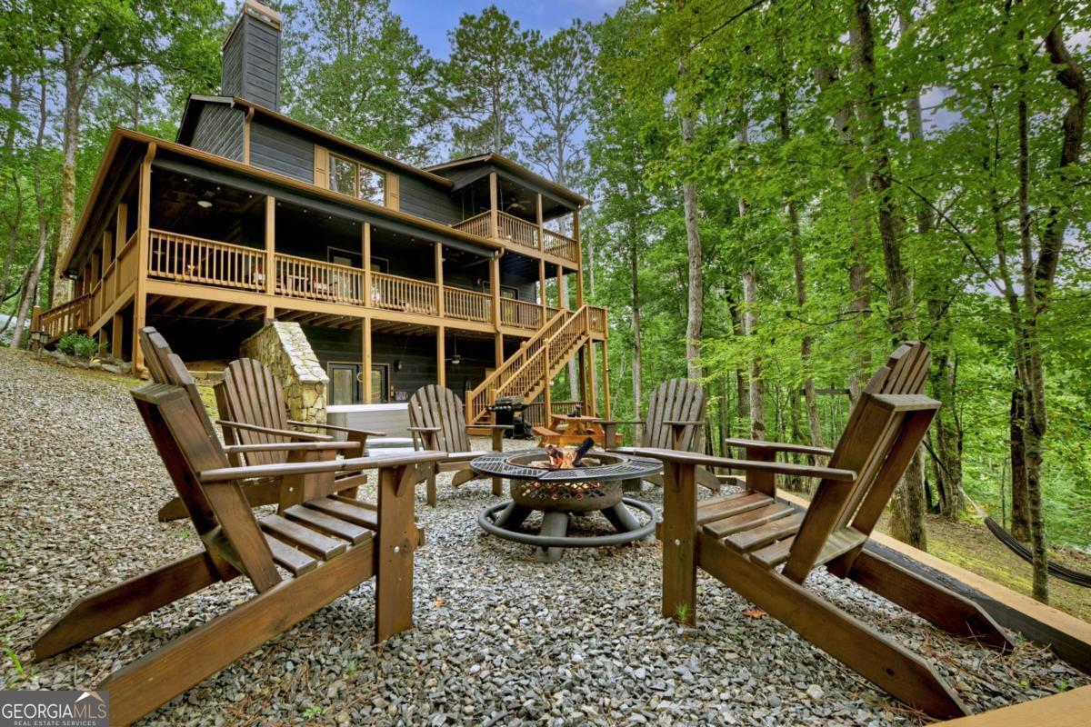 Welcome to your dream mountain retreat in the heart of Coosawattee-a fully renovated 3-bedroom, 3-bath cabin, that perfectly blends rustic charm with modern luxury. This meticulously maintained, 5-star turn-key rental offers an exceptional layout w/ features like three fireplaces, year round partial river views, & the soothing sounds of the Coosawattee River. Recent upgrades include a new roof, Trane HVAC system, fresh paint inside & out, professional dcor throughout, & an updated outdoor entertaining and relaxation space. The inviting wraparound porch overlooks a level, low-maintenance yard ideal for outdoor living, while the interior showcases hardwood floors, tongue-and-groove & drywall finishes, vaulted beam ceilings, & a dramatic two-story gas log fireplace. The chef's kitchen boasts granite countertops, custom cabinets, a large island, pantry, and stainless appliances-including a new dishwasher. The main-level primary suite offers porch access, vaulted ceilings, & a spa-like bathroom w/ marble vanity, tiled floors, and in-closet laundry. Upstairs features a kid-friendly loft and a spacious guest suite with ensuite bath, walk-in closet, private porch, soaking tub, and custom tilework. The finished terrace level serves as a complete in-law suite with tile & luxury vinyl plank flooring, gas log fireplace, full kitchen w/ hickory cabinets & granite, tray/coffered ceilings, guest room, 1 bathroom w/separate water closet and sink, makeup vanity, & custom tile shower. Outside, enjoy an entertainment patio w/ a hot tub, firepit, picnic area, hammock, swings, & solar lighting. Smart-home features include Ecobe thermostats, porch Bluetooth lighting, & 4 Smart Televisions. Enjoy a heated/cooled detached "Zen Den/yoga studio" perfect for yoga, games, or office use heated & cooled w/ mini-split unit. Located in a gated resort community, enjoy river parks, indoor pool, tennis, pickleball, fitness center, game room, & tubing-offering the ultimate mountain lifestyle.