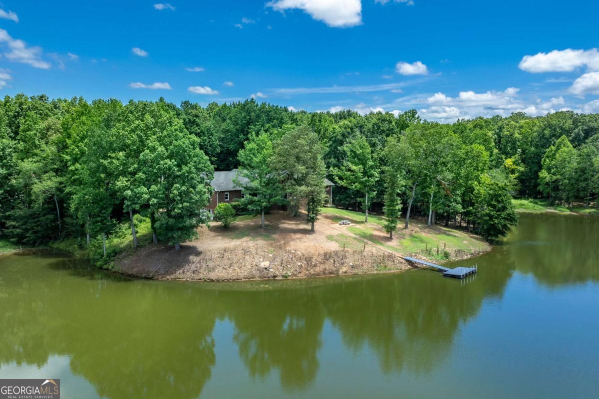 One of a kind property! Four board fence lined with mature fruit trees along paved Harris Road creates inviting entrance to property. Enter through large metal gate between brick Collums and magnolia trees down a 1000 foot paved private drive to the hidden 4-sided Brick ranch home that sits on private knoll overlooking gorgeous 4 acre lake with large private dock. Lake is fully stocked with healthy population of Bass, Catfish and Bluegill that produces trophy catches. Property is a sportsman's paradise with wooded area in back that is home to whitetail deer and turkey for healthy wild game opportunities. Home features 4 extra-large bedrooms and 4 1/2 Baths. Gorgeous hardwood floors and trim features that include fluted door jams, crown molding and solid wooden doors throughout the home. Gorgeous masonry fireplace in family room. Large formal dining room and separate den/office room if you work from home. Sunroom with stone floor spans along the back of home overlooking rear park like setting and gorgeous lake and party dock. Country kitchen features island and liberal counter space for the chef in the family. Large laundry room on main level has mud sink and cabinetry for extra storage. Full basement is unfinished but offers bathroom and canning kitchen with a secure storm shelter with concrete ceiling that could be converted into a gun vault. High basement ceilings and large open area lends space for the ultimate man cave or in-law suite with garage door and private driveway access. 40 x 50 clear span barn/shop is insulated with full bath, tack room, work bench, high rollup doors and heat unit. Also has 10 x 50 covered front shed with concrete floor in front along with shed on back that would easily convert to equestrian stalls. Pasture in front now used for cattle would make nice paddock or riding ring area for horses. So much to mention it would be easy to forget about the hidden one room fish cabin on the back side of the lake hidden from the outside world! Great place for that off the grid experience to offer friends or family members up for the weekend! This 45 acre investment with the lake as a wonderful centerpiece offers many possibilities!