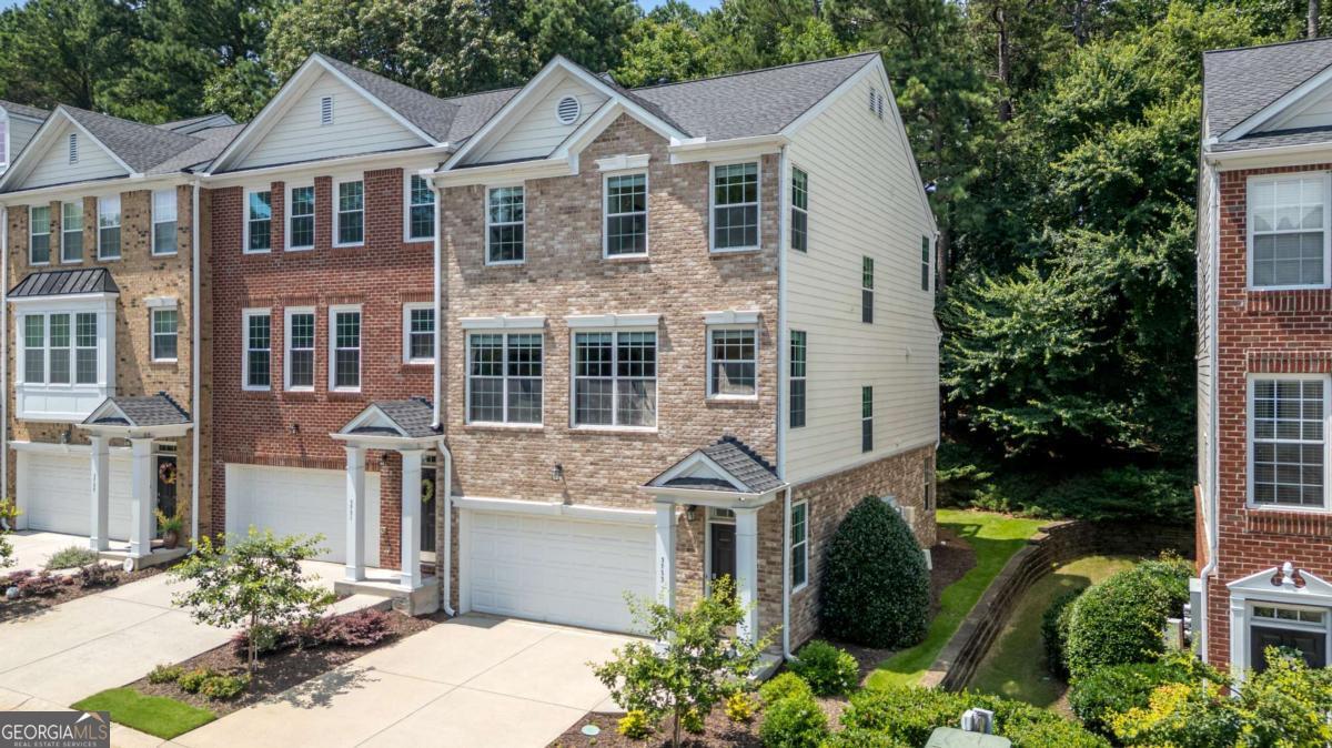 ***$10,000 towards Buyer's Closing Costs plus New Flooring Upgrade to COREtec LVP on the Main Level with a full-price offer!*** Luxury end-unit townhome in the gated Chattahoochee Bluffs community, offering rare privacy, wooded views, and an abundance of natural light throughout. This spacious 3-bedroom, 2.5-bath home backs up to the Chattahoochee National Forest and is just steps to the nature trails and river access. As an end-unit, it features extra windows and enhanced natural light, especially in the living room and vaulted primary suite. The main level offers a large, open living space with a beautiful raised brick fireplace, a dining area, and a generous kitchen with upgraded stainless steel appliances (2020), pendant lighting over the breakfast bar, and upgraded cabinet pull drawers. Step outside onto the oversized deck that overlooks a serene wooded backdrop-ideal for entertaining or relaxing. The lower level features a massive finished bonus room perfect for a media room, game room, or playroom, plus a large storage closet that could easily be converted into a full bath. There is also a large patio off the basement level offering even more private outdoor space. Upstairs, the spacious primary suite includes vaulted ceilings, extra windows, and an upgraded closet system. Builder upgrades include open stair railings, ceiling fans throughout, hardwood floors in the hallway, tile flooring in the primary bathroom, and additional electrical outlets and thoughtfully placed light switches. The home has been meticulously maintained with major system updates including HVAC (2020), water heater (2019), and roof replacement by the HOA (2021). Enjoy community amenities such as a clubhouse, pool, fitness center, and gated security-all in a prime location close to I-75, I-285, Vinings, Buckhead, Midtown, and within walking distance to The Battery and Braves Stadium. This move-in ready home combines luxury, convenience, and peaceful nature views in one of the most desirable areas around. Hurry, END-UNITS with a nature view like this won't last long!!!