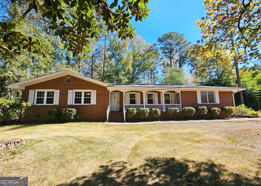 Welcome home to this charming all-brick 3-bedroom, 2-bath ranch!  From the moment you arrive, you'll love the inviting front porch and the warm, open layout that connects the living room and dining area-perfect for gatherings and everyday living. The cozy den features beautiful built-in bookcases and sliding doors that lead to a spacious screened-in porch, ideal for relaxing or entertaining. Step outside to a fenced backyard surrounded by mature trees, offering both privacy and a lovely view of the neighborhood. Nestled on a picturesque wooded lot and located just 17 miles from downtown Atlanta, this home combines comfort, charm, and convenience!