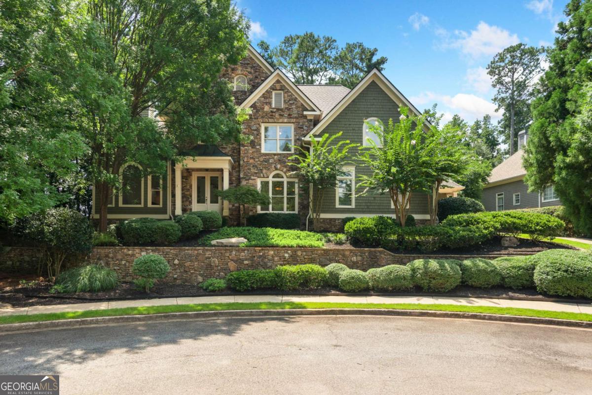 It is rare to find a home that blends timeless beauty with true craftsmanship-yet this residence delivers from the moment you step inside. A sweeping curved staircase, gleaming site-finished hardwoods, coffered ceilings, and a dramatic stacked-stone fireplace set the tone for a home that feels both sophisticated and refreshingly unique. Northeast facing for incredible morning sunlight. The main-level primary suite is a private retreat, featuring a soaring cathedral ceiling, designer lighting, a cozy fireplace, and a private door leading to the covered porch. The spa-inspired bath offers a double walk-in shower, soaking tub, dual vanities, and a fully customized walk-in closet. At the heart of the home, the kitchen balances elegance and function with white cabinetry, stone countertops, double ovens, a gas cooktop, pop-up vent, and warming drawer. A built-in hutch showcases your treasures, while the oversized walk-in pantry disguised as cabinetry keeps everything neatly tucked away. Flowing seamlessly into the family room, it is ideal for intimate evenings or lively gatherings. Additional main-level spaces include a formal dining room, refined living room, and a mudroom with a large laundry, all finished with meticulous trim and high ceilings. Upstairs, generously sized bedrooms and baths provide comfort and privacy for family or guests. The upper level kids entertainment room is ideal for all the toys, a hang out space and ideal study space. Designed to live beautifully through every stage of life, this home offers abundant space when loved ones are near, yet feels perfectly scaled for everyday living. An expansive rear porch overlooks the private backyard, while the daylight, walk-out basement awaits your vision for future expansion. Three car, kitchen level garage with one bay heated and cooled! Nestled at the end of a quiet cul-de-sac in an enclave of custom homes, this residence offers the prestige of a Roswell address paired with the advantage of Cobb County taxes, all within the sought-after Lassiter High School district. New roof installed in April All new paint and carpet and just-refinished wood floors make this home an easy decision. Don't miss your opportunity to see this beautiful home today.