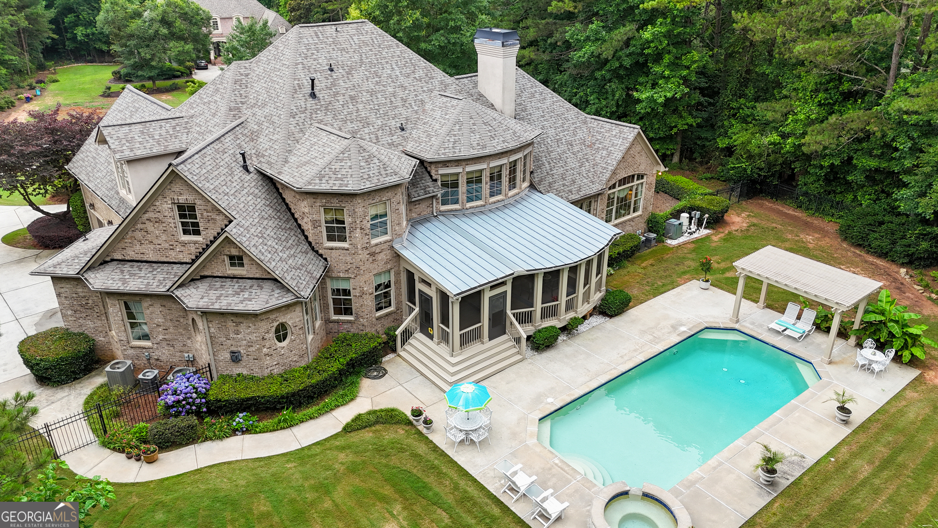 LUXURY AT IT'S FINEST in the Prestigious, gated River Oaks Community! Don't miss your opportunity to own an award-winning Street of Dreams custom designed, Move-In-Ready home with two Primary Bedrooms on the Main, a brand new roof, salt water pool, three car garage and a 3,500 sq ft finished basement! This four sided brick home with stunning architectural street appeal is perfectly situated on 2.36 acres, providing privacy and plenty of room to entertain! Being offered at $146,694 below a recent appraisal, so you will have immediate equity! From the circular driveway, step on to an inviting front porch perfect for afternoon ice tea and watching the day go by. Enter through two impressive iron scroll front doors and be WOWED by the soaring ceilings and WALL OF WINDOWS overlooking your back yard entertainment retreat! With hardwood floors throughout the main floor, a formal living room, wet bar, plus a separate dining room that seats 12, you will immediately be impressed! Walk into the expansive great room and be delighted by the abundance of natural light, the stately fireplace, and beautiful view from the floor to ceiling windows. An enormous screened in porch is waiting for you to enjoy! Step into a gourmet kitchen any home owner would be proud to own, complete with huge island that seats 4, custom cabinetry with granite counters, stainless high-end appliances and an adorable eat-in breakfast nook, overlooking the perfectly landscaped back yard! A wonderfully cozy den with vaulted ceilings accented by rustic beams and a stone gas fireplace is going to be your favorite hang out spot in the home! Also, on the Main you will find the stunning primary on suite with a wall of windows overlooking your pool, a separate sitting room, a beautiful bathroom with his and hers vanities, vaulted ceilings, and relaxing soaking tub! A second primary on suite makes for the perfect guest suite, in-law or room mate plan. Upstairs, you will find three oversized bedrooms, each with their own bathroom, an open loft with hallway that leads to the perfect space for an office, art studio, or you can use your imagination! The walk out terrace level is over 3,500 sq ft, and features a fireplace, mini bar, and a game room, perfect for pool, ping pong, playing cards, and having fun! A media room, wine room, office, and huge gym, as well as a full bath and tons of storage, make this a one of a kind home! OUTSIDE is a dream come true, with a huge oversized salt water pool, hot tub/spa with waterfall, professionally landscaped palm trees, gorgeous flowers, ornamental bushes, and an architectural fence. Woods behind you create a very private outdoor retreat! ALL THIS in the perfect Fayette County location boasting award-winning schools, minutes from I-85, Town of Trilith, shopping, and dining! Call right away to see this home today!