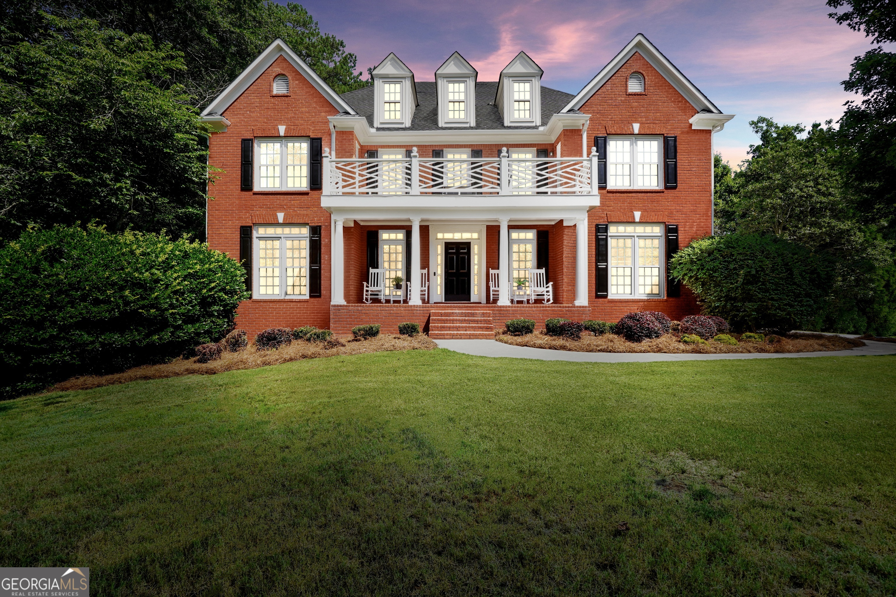 Step into timeless sophistication on one of the largest corner lots in The Estates. This stately three-sided brick home sits on approximately 1.42 acres of beautifully landscaped grounds, offering space, privacy, and refined living. With a finished terrace level and multiple areas for entertaining, the home delivers thoughtful design and functionality across all three floors. A spacious front porch leads into a grand foyer. To the left, a formal sitting room flows into a large dining room, perfect for hosting gatherings and special occasions. The heart of the home is the expansive kitchen, featuring quartz countertops, stainless steel appliances, an oversized island, and abundant cabinetry. A walk-in pantry and built-in desk area enhance both style and utility, while the sunlit breakfast nook offers views of the backyard. The kitchen opens to a warm living room with shiplap accent walls, an updated tile fireplace, and generous natural light. From here, step out to the covered side porch or open patio for seamless indoor-outdoor living. A main-level half bath and direct access to the garage add everyday convenience. Upstairs, the oversized primary suite is a peaceful retreat with a sitting area, dual walk-in closets, and a spa-like bath featuring a soaking tub, walk-in tile shower, dual vanities, and a dedicated makeup space. Beyond the bathroom, a private flex room currently used as a home office opens to a rear-facing terrace overlooking the backyard. Both the primary and front bedrooms enjoy access to an uncovered front terrace. The front bedroom includes its own private en suite, while the other two bedrooms share a spacious Jack and Jill bathroom. The finished terrace level is designed for comfort and entertainment. It includes a large living area, full bathroom, eat-in kitchenette, and a dedicated theater room. A large storage room and a boat door provide added utility, and this level opens directly to the expansive fenced-in backyard-ideal for entertaining or enjoying quiet evenings outdoors. Every element of this home has been curated to offer refined comfort, practical living, and a lifestyle of everyday luxury.