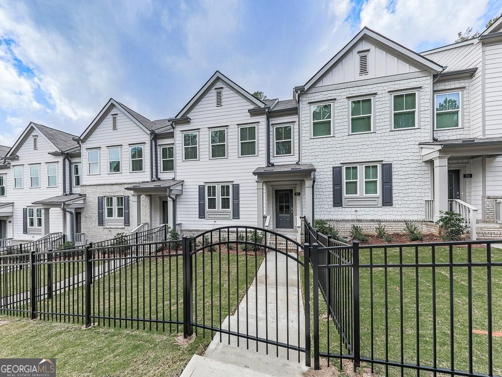 Beautiful Townhome only 3 years old in Towne Lake Community! Gorgeous high end town home with a fenced front courtyard! Main-level includes an entry foyer, incredible kitchen with grey cabinets, tile backsplash, quartz countertops, a large island with a breakfast bar, all stainless- steel appliances, including refrigerator, washer and dryer, dining area and guest bathroom. An incredible family room with a built-in modern fireplace that leads to a large deck overlooking woods. Upstairs includes a lovely owner's suite with trey ceiling and en-suite bath, a secondary bedroom with a full bath and laundry room. Terrace level includes the perfect flex room for a game room or guestroom, media room, fitness area, a full bath, oversize closet and a 2 -car garage. The location is fantastic! Nature trails across the street leading to Downtown Woodstock, shopping, restaurants, entertainment and so much more. Close to easy access to I-575.