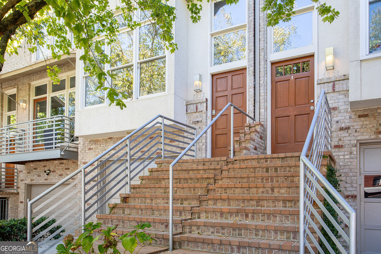 Brooklyn Energy Meets Brookhaven Charm! Step inside this light-filled three-story townhome that blends a cool NYC vibe with the warmth of Southern living. Exposed brick walls, real hardwood floors throughout, and sunlight streaming through oversized windows create an airy, modern aesthetic that still feels undeniably cozy. The main level offers true open-concept living with a spacious kitchen flowing seamlessly into the living area anchored by a gas fireplace. The living opens to a large private patio that's perfect for grilling, entertaining, or simply enjoying the lush greenery that surrounds the home. A dedicated dining room with a striking sputnik light fixture adds a stylish touch for dinner parties or quiet nights in. Upstairs, you'll find two generous bedrooms, each with ensuite bathrooms, custom drapes, and hardwood floors. The primary suite features a large closet and bathroom. Downstairs, the bonus room offers flexible living that is ideal as a home office, gym, or third bedroom, complete with a convenient half bath. The one-car garage is extra deep, accommodating two smaller vehicles or one car plus storage. Outside, a fully fenced private backyard provides the perfect retreat for pets or morning coffee surrounded by trees. Located in Brookhaven Village, this home offers the best of both worlds: walkability to top-rated restaurants, shops, and parks, yet tucked within a quiet, upscale neighborhood. With easy access to Buckhead, Midtown, and major hospitals, this is city living without compromise. You truly have to experience it in person and the longer you stay, the more you'll fall in love.