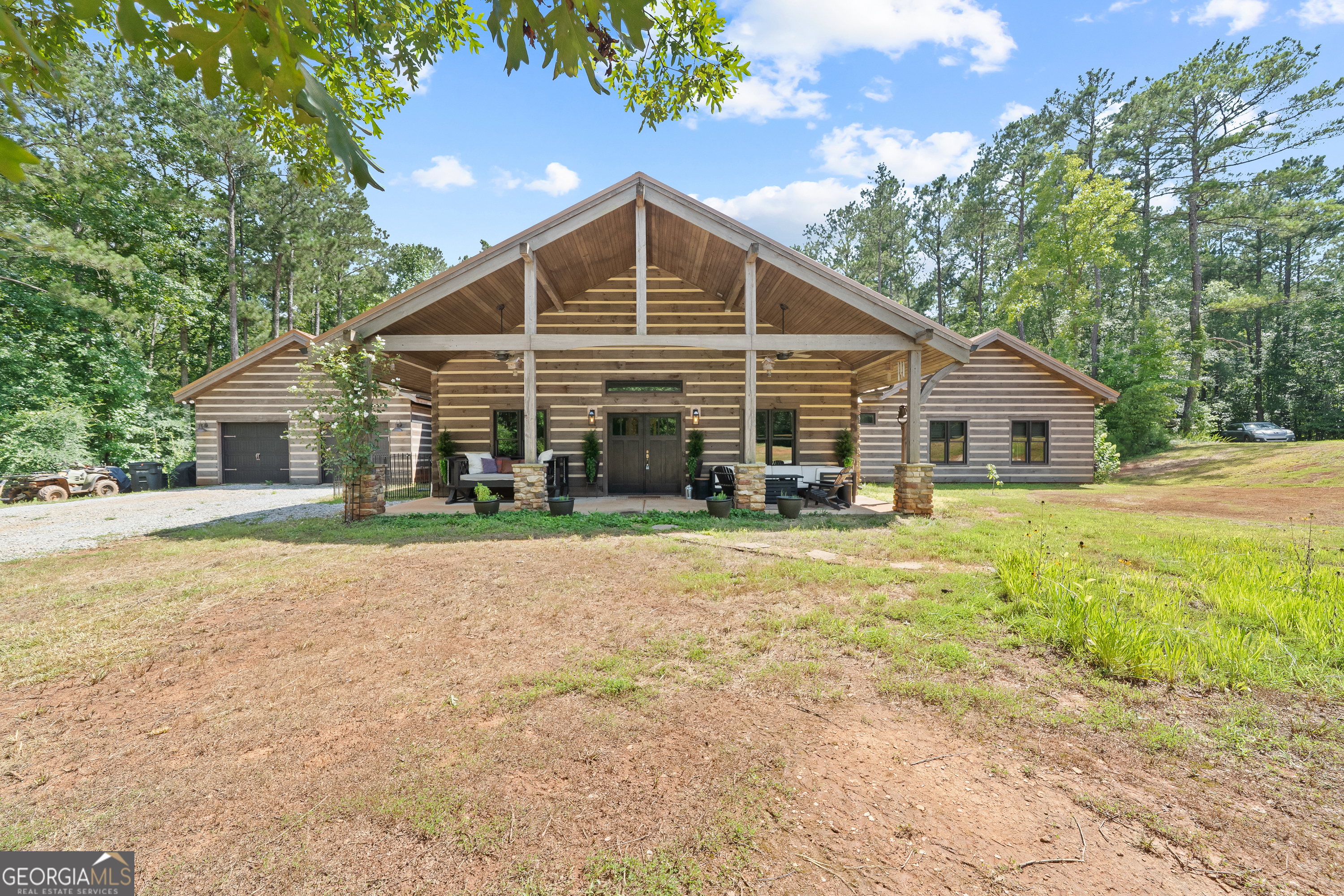 Escape to your dream countryside copper cabin in the woods! Do not miss out on this a meticulously maintained ranch-style log cabin home built in 2018, nestled on a serene 40-acre wooded estate in the upscale River Farm area of Morgan County. Experience country elegance with this beautifully designed 4-bedroom, 3-bath home, ideally set on 40 serene acres. This custom designed home offers over 2,800 square feet of refined comfort, open living, tons of natural light and peaceful outdoor enjoyment. Step inside to an open-concept layout featuring soaring vaulted ceilings, hardwood floors, and a large cozy stone fireplace. The gourmet kitchen is a chef's dream with a large island, granite countertops, stainless appliances, brand new gas stove, under cabinet lighting and generous cabinetry. The spacious primary suite includes vaulted ceilings, walk in closet with custom storage, a spa-like bath with dual vanities, a claw foot tub, and a walk-in shower. Two additional bedrooms offer spacious closets with container storage and plenty of natural light. The 4th bedroom could be a flex space with options for a bonus room, flexibility for guests, a home office, or recreation. This oversized room has endless possibilities! Outside, unwind on the covered patio overlooking your private wooded retreat-perfect for entertaining, relaxing, or watching Georgia sunsets. And lets not forget about the many fruit trees, trails for walking or riding, river fun and more! This home offers RV water and electric hook up, spray foam insulation 2 HVAC units, 8 foot solid doors throughout, wired for whole home generator, 16x40 barn/shop with electricity and stubbed for bath, wood shed and so much more! Please see additional documents for a list of extras this home has to offer. Do not wait to come see! This is more than a home-it's a lifestyle. Schedule your private tour today and fall in love with the tranquility of Madison living.