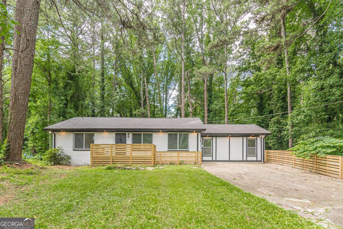 This FULLY RENOVATED brick ranch offers modern comfort and custom style on a full basement, with NEW HVAC and NEW PLUMPING! A long driveway provides ample parking, bordered by a stylish wood partition. The freshly painted exterior with bold, contrasting trim and a front patio with modern wood railing create instant curb appeal. Step inside to an open concept main living area with a desirable split-bedroom floor plan. Gorgeous LVP flooring, designer lighting, and a show-stopping OVERSIZED QUARTZ WATERFALL ISLAND set the tone for elevated everyday living. The kitchen boasts sleek new stainless steel appliances, soft-close cabinetry, a classic subway tile backsplash, and a walk-in pantry for all your storage needs. The luxurious primary suite is the showstopper of the home, featuring French door entry, a decorative fireplace (with the option to add an electric insert), custom barn doors, double vanity, and marble-like tile that surrounds the incredible wet room complete with a waterfall shower head and a freestanding soaking tub for a spa like experience in the comfort of your own home. Two additional bedrooms and a stylish full bath round out the main level. The full unfinished basement is already framed and includes a laundry hookup, offering a blank slate to expand your living space and build INSTANT EQUITY! Enjoy a spacious back patio with matching wood railing, surrounded by shade trees and private wooded views, perfect for dining or relaxing under the stars. No HOA, and ideally located near I-20 & I-285 and other major highways for an easy commute. Nearby schools, shopping, dining, grocery options, and healthcare. Minutes from Mid-Town! With custom features, flexible floor plan, and undeniable convenience, this home is built to impress and entertain, no matter the occasion!