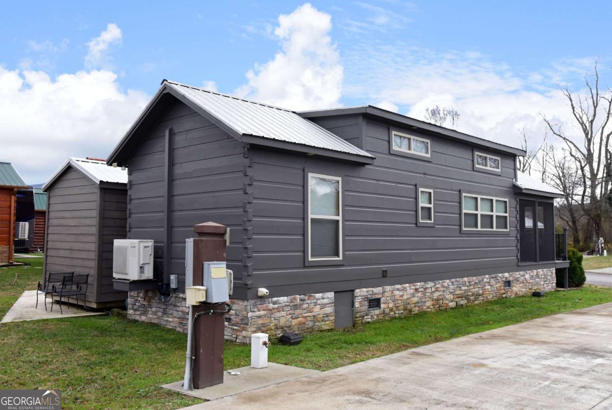 Escape to tranquility inside the CCRV with this delightful tiny home, nestled in its peaceful environment, where the soothing sounds of a nearby creek create the perfect backdrop for relaxation. This property features a sizable concrete slab, ideal for parking a 45-foot RV and an additional vehicle, making it perfect for adventurers and travelers alike. The parcel includes a practical shed, home to a golf cart, that can be negotiated in the purchase. The cabin showcases rustic charm with its all-wood construction and beautiful wood accents. Step inside to discover a cozy full-size kitchen thoughtfully designed with ample space for a couple. Embrace a simpler lifestyle in this inviting retreat, perfect for those looking to unwind in nature while enjoying modern conveniences. The community provides amenities that will suit the whole family. Spa, Sauna, Fitness Center, Clubhouse to host parties or attend events; Trout streams for the fisherman; Salt water pool; Tennis & golf, and its onsite laundry facility! This Great location is less than 5 minutes from Blairsville. Find your retreat at Crossing Creeks RV & Spas.