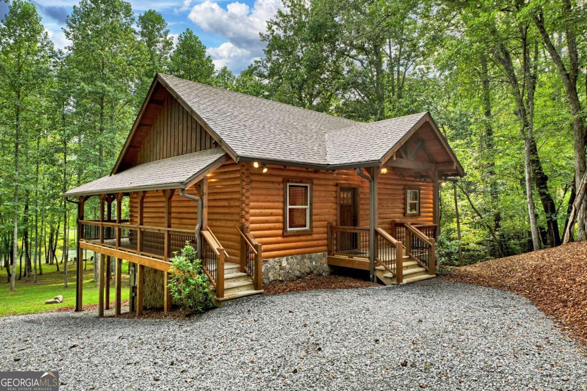Nestled along the pristine shoreline of the Toccoa River, this true log home blends timeless craftsmanship with effortless mountain living. Built with Satterwhite Logs and accented by Tennessee fieldstone, the residence has been meticulously maintained and showcases over 100 feet of direct river frontage. Set on gentle, usable acreage with a rare flat backyard, the property offers an ideal riverside lifestyle. A small creek winds through the land, flowing gracefully into the Toccoa-perfect for nature lovers and those seeking a serene retreat. Inside, warm red oak hardwood floors and a warm-rustic aesthetic create a welcoming atmosphere. The kitchen pairs bird-pecked hickory cabinetry with stone countertops for a touch of natural refinement. The open-concept design extends to a spacious great room and continues to the wraparound deck, where lush backyard and river views set the backdrop for relaxation. The terrace level expands the living space with a full den and a walk-out patio, ideal for entertaining or quiet evenings by the water. With fiber internet service (300/300 mb) already in place, the home is as connected as it is peaceful. Offered fully furnished, less than ten minutes to Downtown Blue Ridge and Lake Blue Ridge, this riverside cabin is ready for immediate enjoyment-whether as a full-time residence, weekend escape, or short-term rental opportunity.