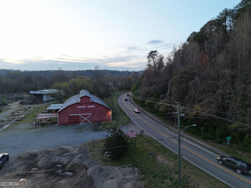 For the first time in history, 400 River St in Ellijay, GA is available for purchase-offering an unparalleled chance to own one of the most iconic and historic commercial properties in the area. Originally built in 1895, this massive 6,100 sq ft former lumber mill still showcases its original timber beams and trusses, echoing the craftsmanship and industry of a bygone era.    Situated on 14.09 acres within the city limits, this unique property boasts 1445+ Feet of frontage on the Cartecay River, bordering the CSX railroad, and offers some of the best and most visible road frontage at over 1665 feet in downtown Ellijay. The land includes flat open areas ideal for expansion or development, and an additional 3.46-acre terraced parcel on the opposite side of River Street.    Currently, the property features two land leases generating income: a used car dealership operating out of a commercial office building, and a small cabin being utilized as a spa. Both businesses add immediate value and activity to the site, with flexibility for future uses.    Whether you're envisioning a mixed-use development, boutique hotel, restaurant and event venue, retail center, or preserving and restoring the mill as a historic destination, this property offers incredible flexibility, location, and potential.    Zoned within the city limits, with river frontage, historic charm, and over 14 acres of prime land, this is truly a once-in-a-generation commercial opportunity in the heart of Ellijay's growing downtown corridor.    Contact us today for a private tour and to learn more about this exceptional piece of North Georgia history.